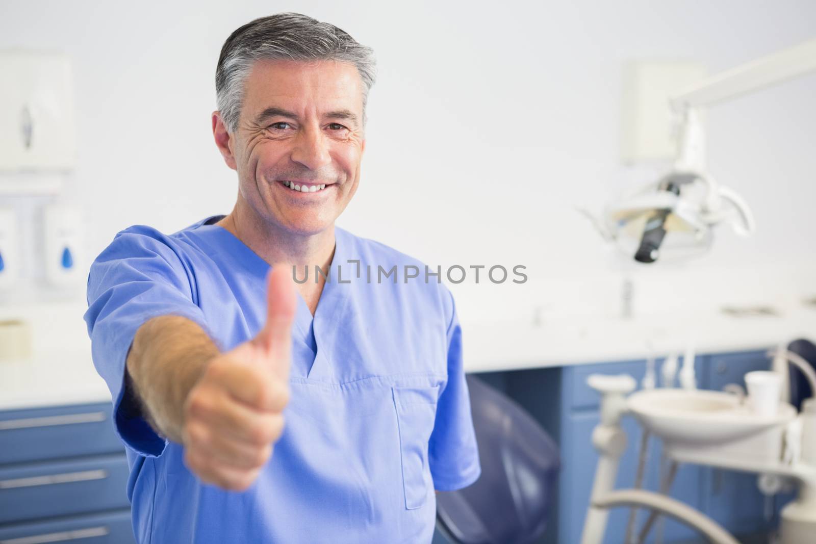 Portrait of happy dentist with thumbs up in dental clinic