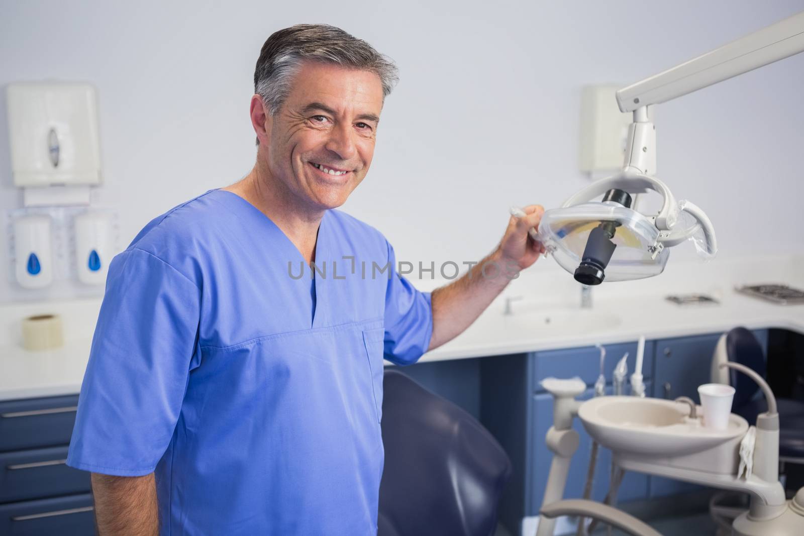 Portrait of a friendly dentist holding light in dental clinic