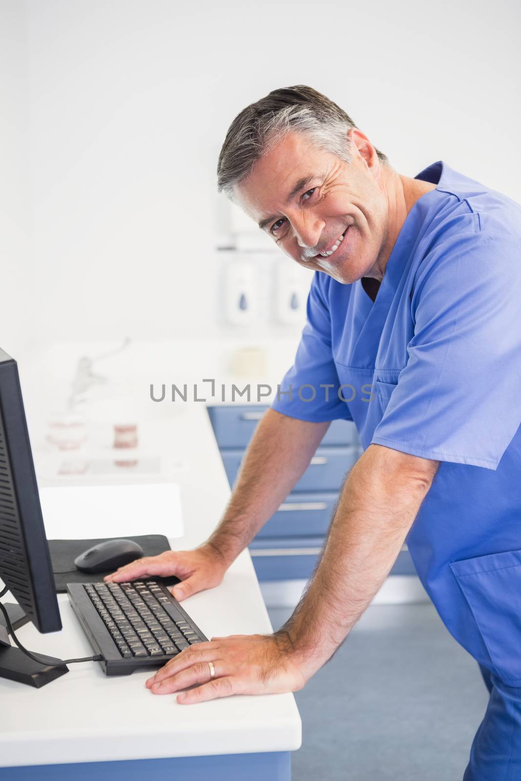 Portrait of a smiling dentist using computer by Wavebreakmedia
