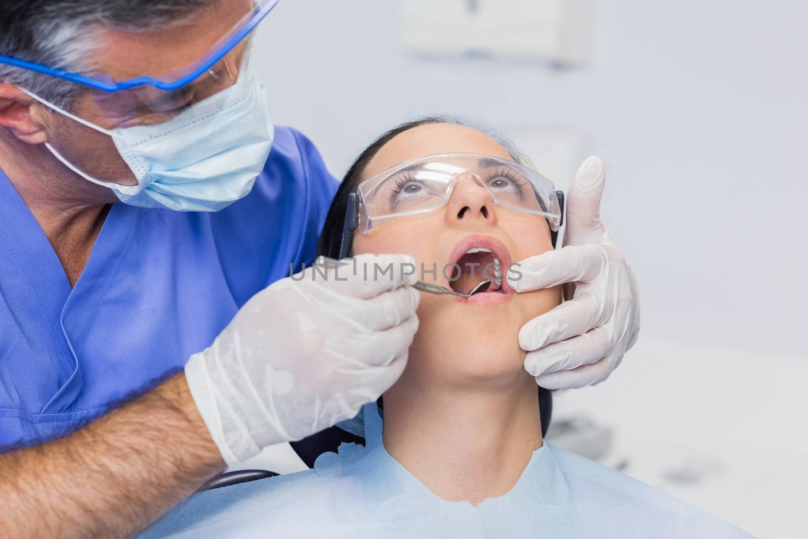 Dentist examining a patient with angle mirror in dental clinic