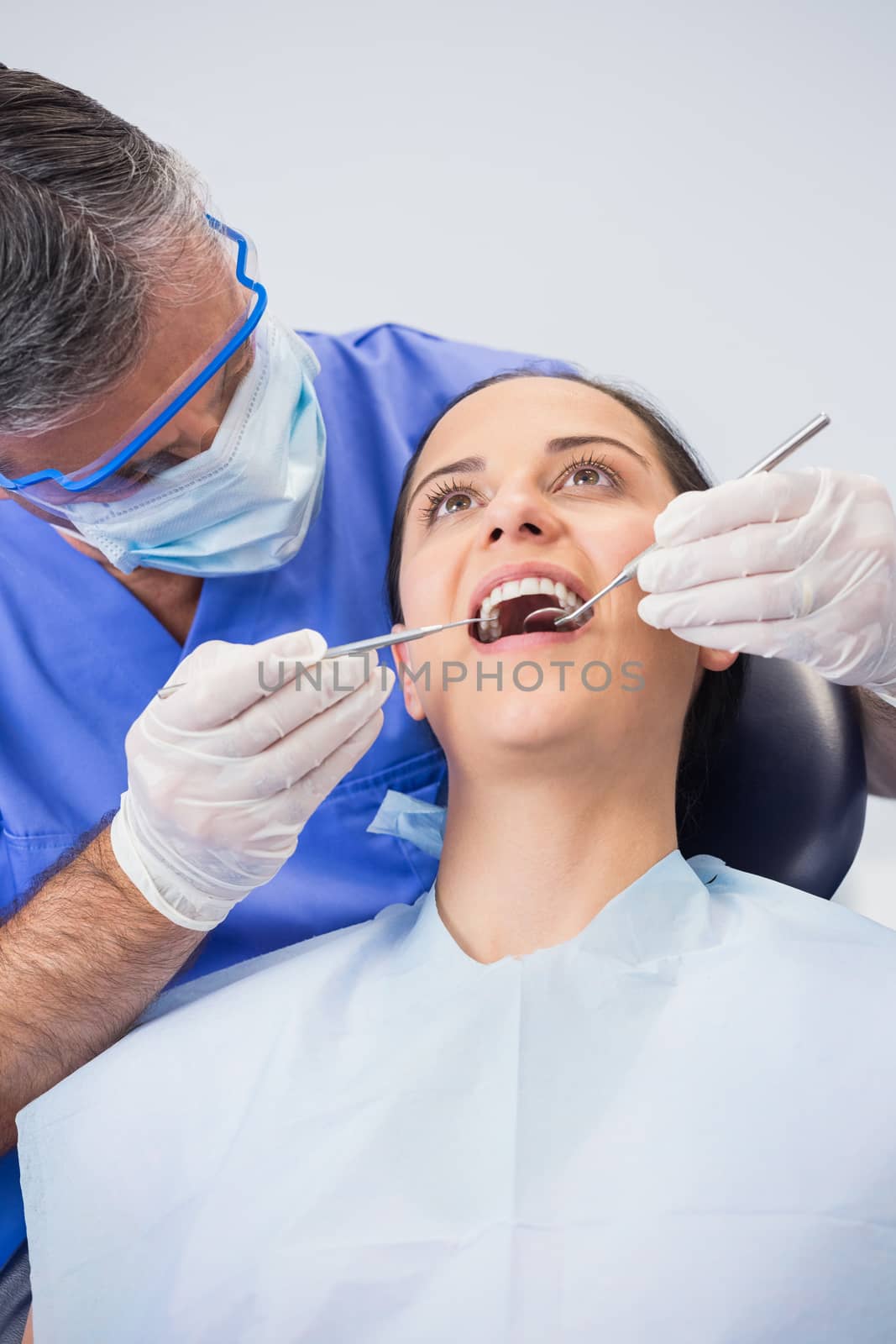 Dentist examining a patient with angle mirror and sickle probe in dental clinic