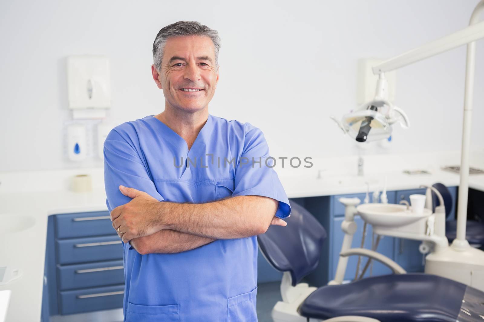 Portrait of a friendly dentist with arms crossed in dental clinic
