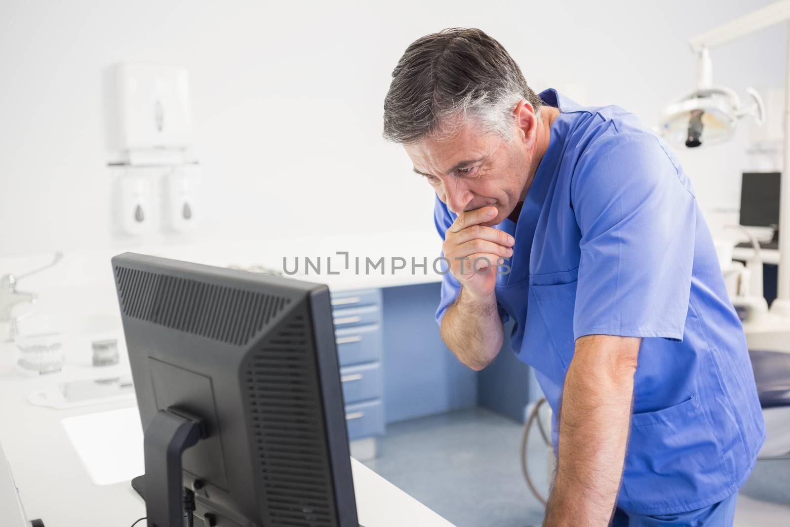 Thoughtful dentist using computer  by Wavebreakmedia