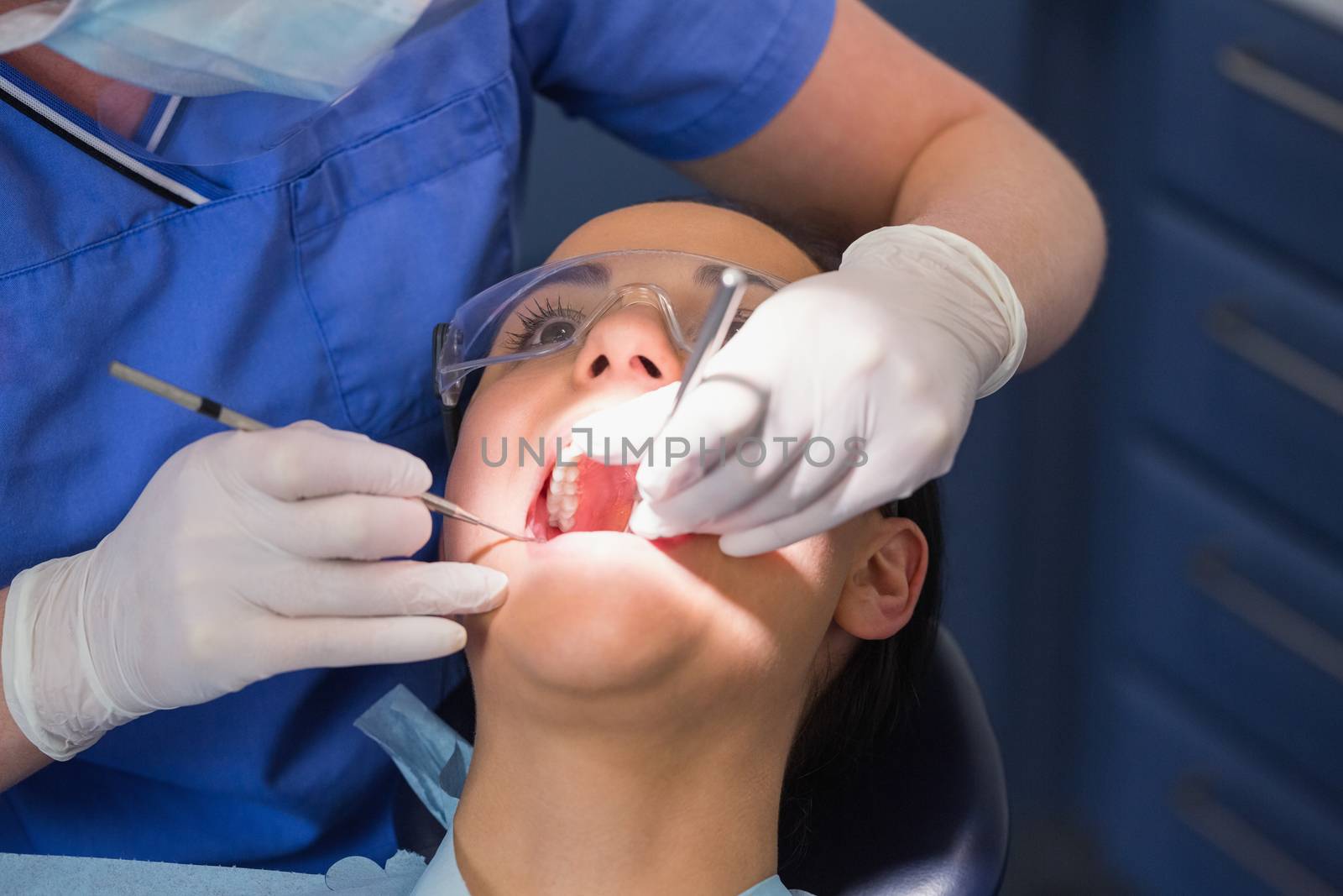 Dentist examining a patient with angle mirror and sickle probe by Wavebreakmedia