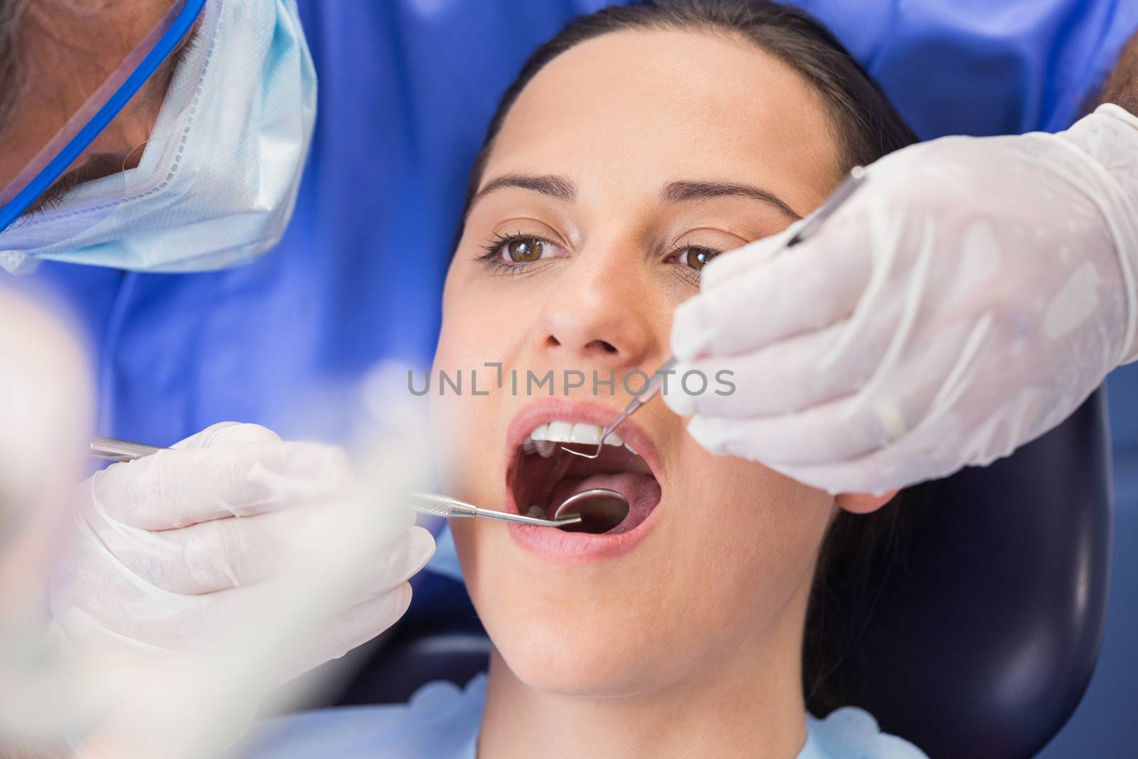 Dentist examining a patient with angle mirror and sickle probe by Wavebreakmedia
