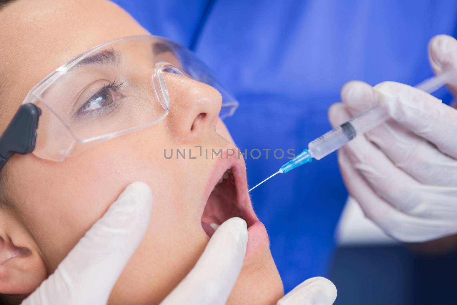 Dentist doing injection to his patient  by Wavebreakmedia