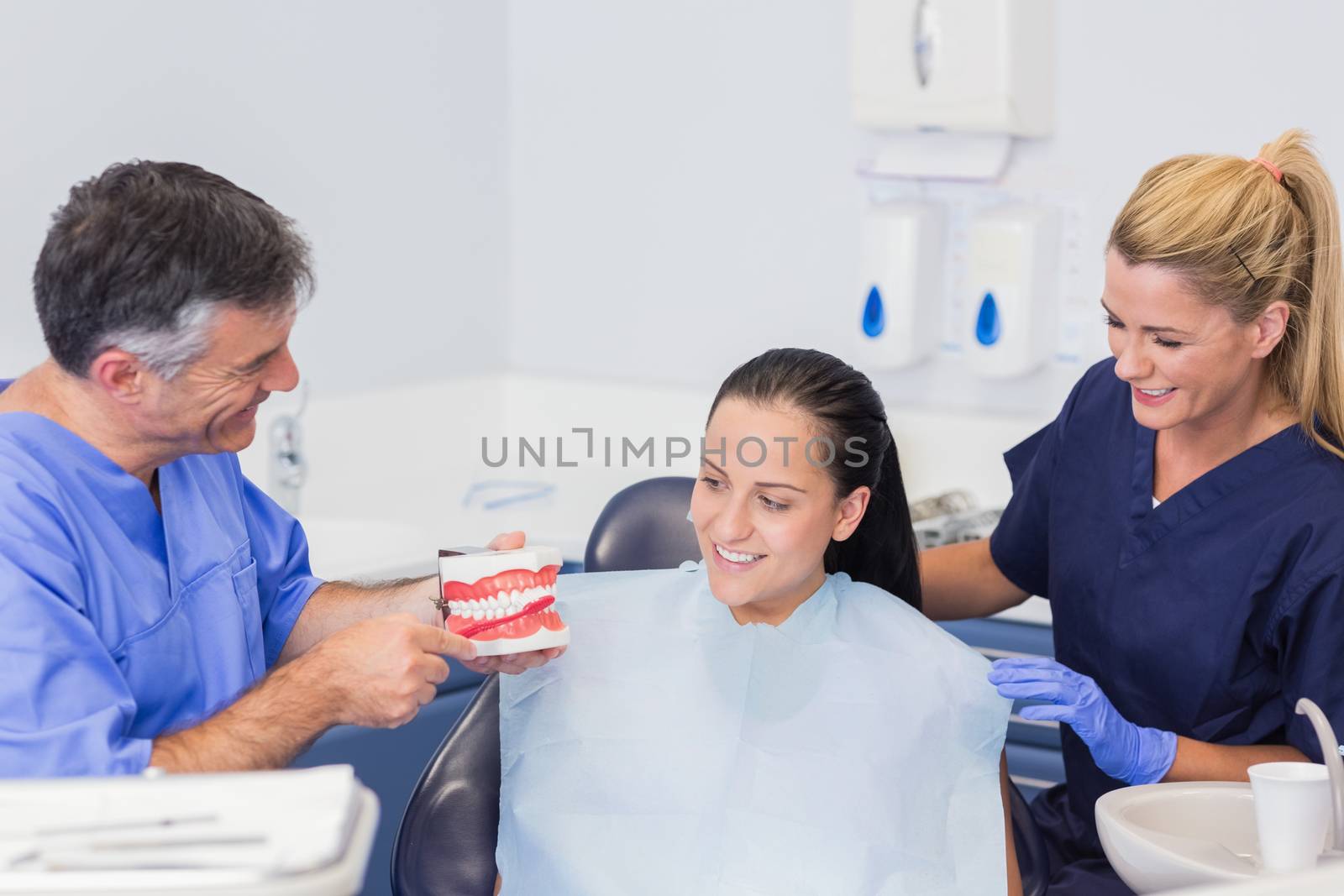 Dentist and nurse explaining to their patient how use toothbrush with a model in dental clinic