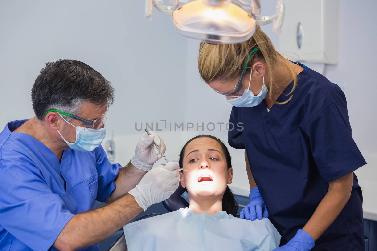 Dentist and nurse examining a scared patient  by Wavebreakmedia