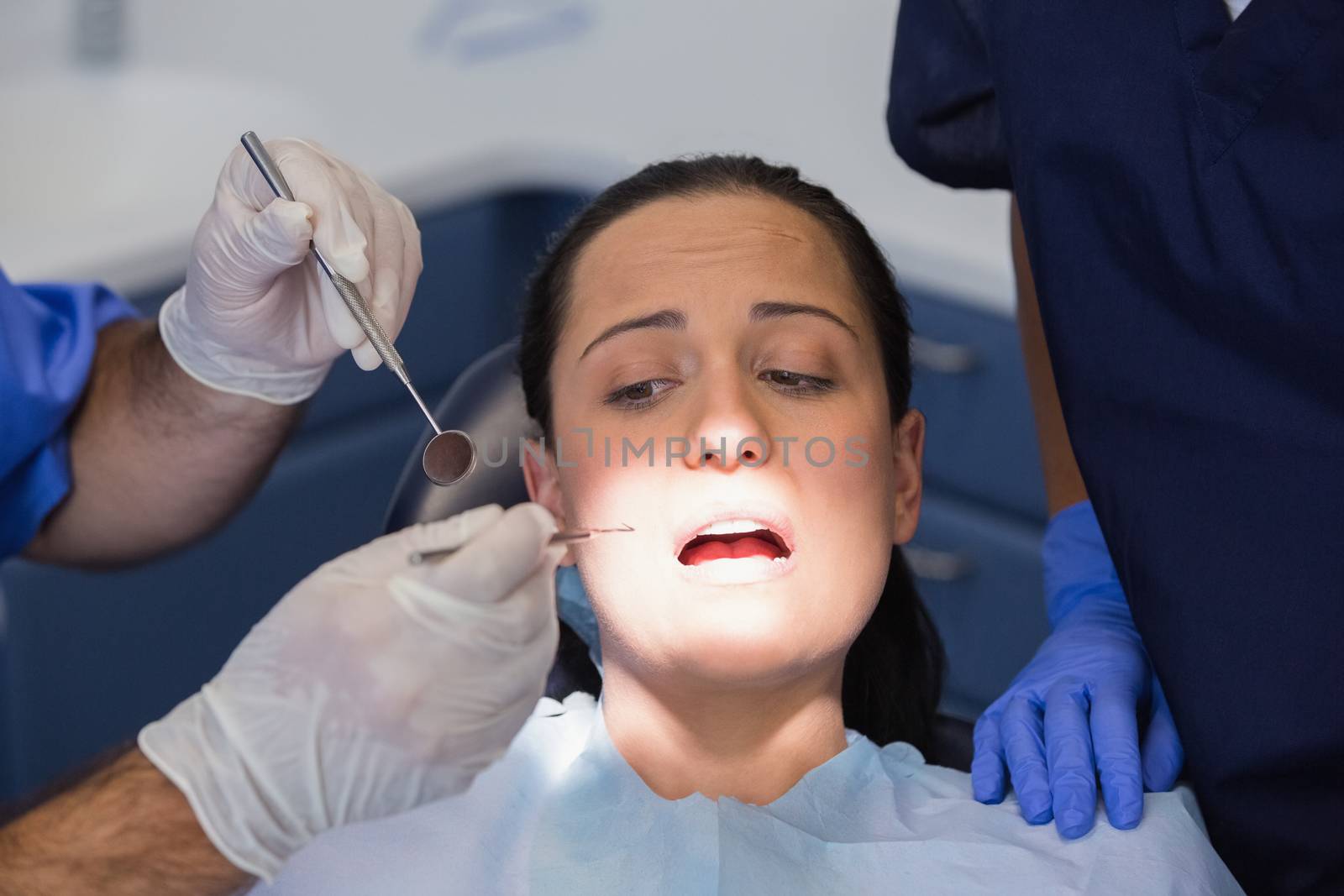 Dentist and nurse examining a scared patient in dental clinic