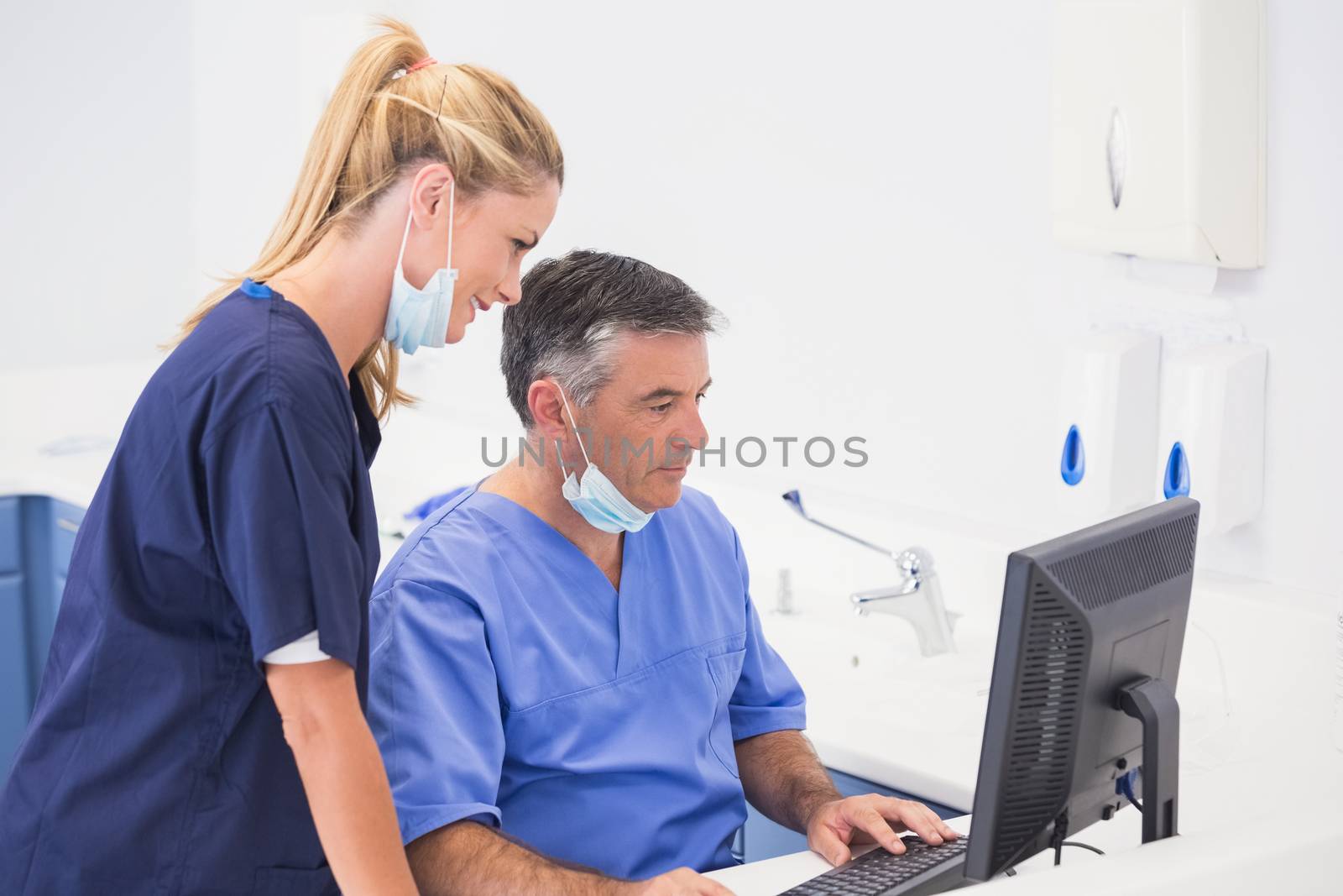 Smiling co-workers using computer in dental clinic