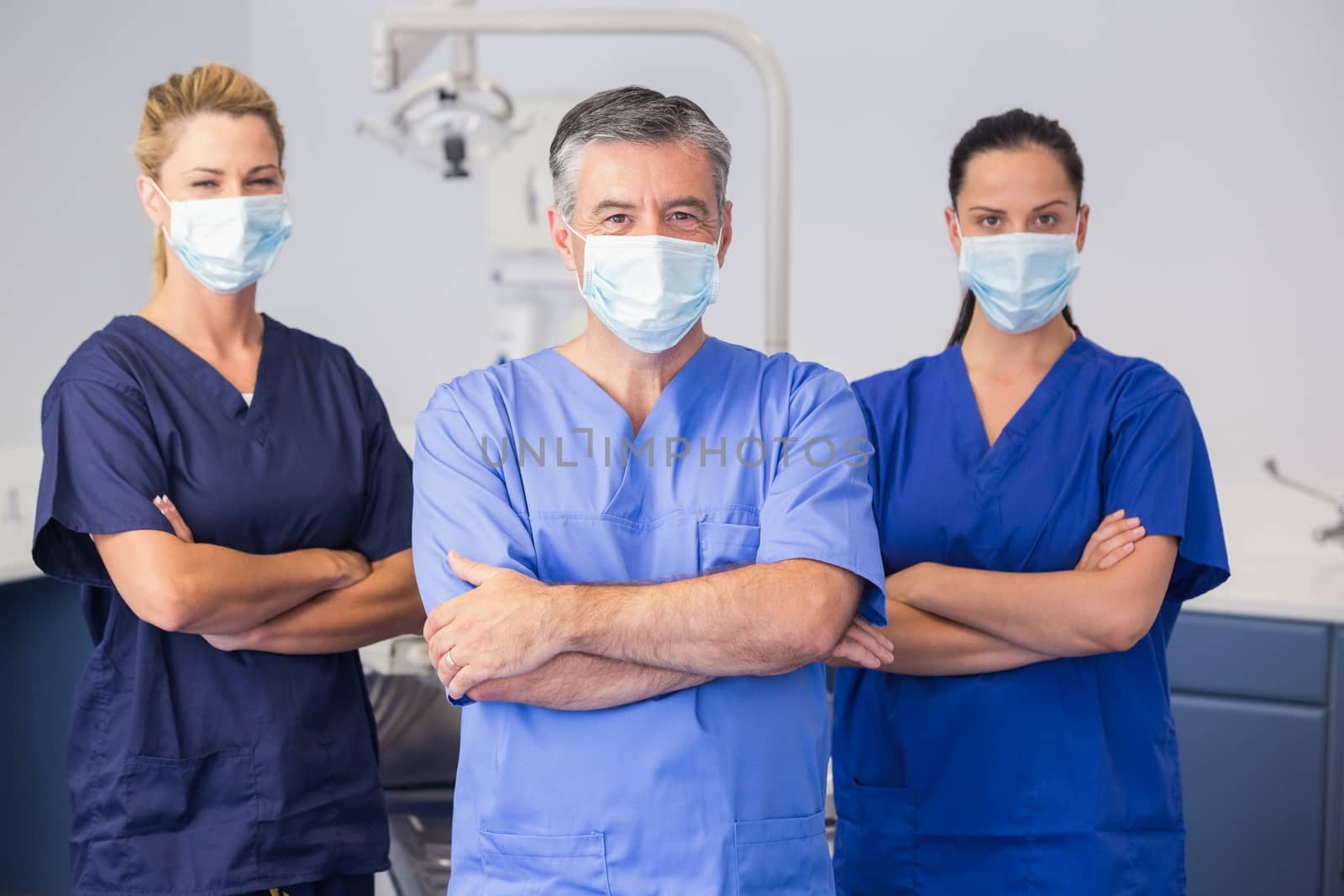 Co-workers wearing surgical mask with arms crossed by Wavebreakmedia