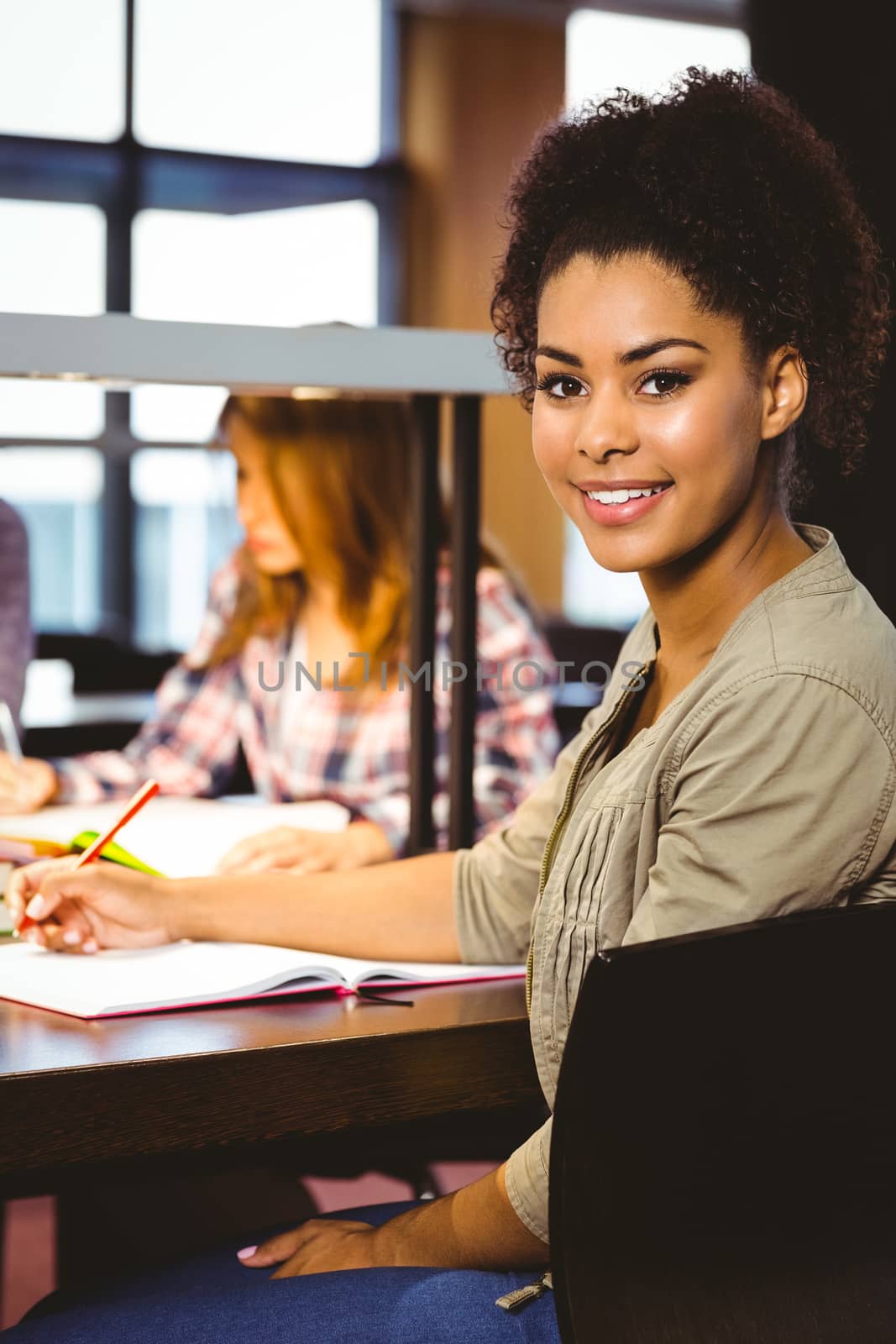 Portrait of a smiling student sitting at desk looking at camera by Wavebreakmedia