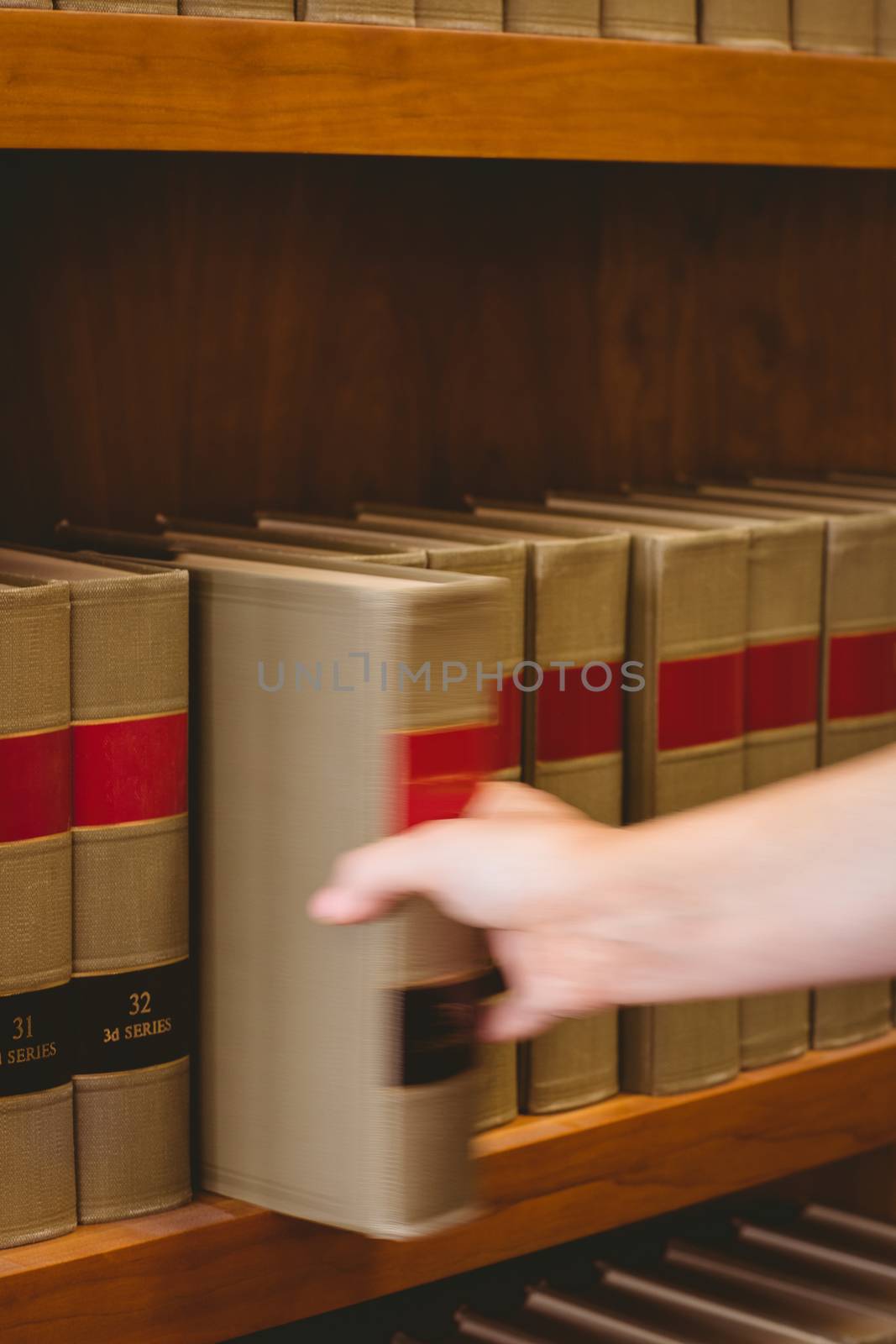 Hand taking a book from bookshelf in the library