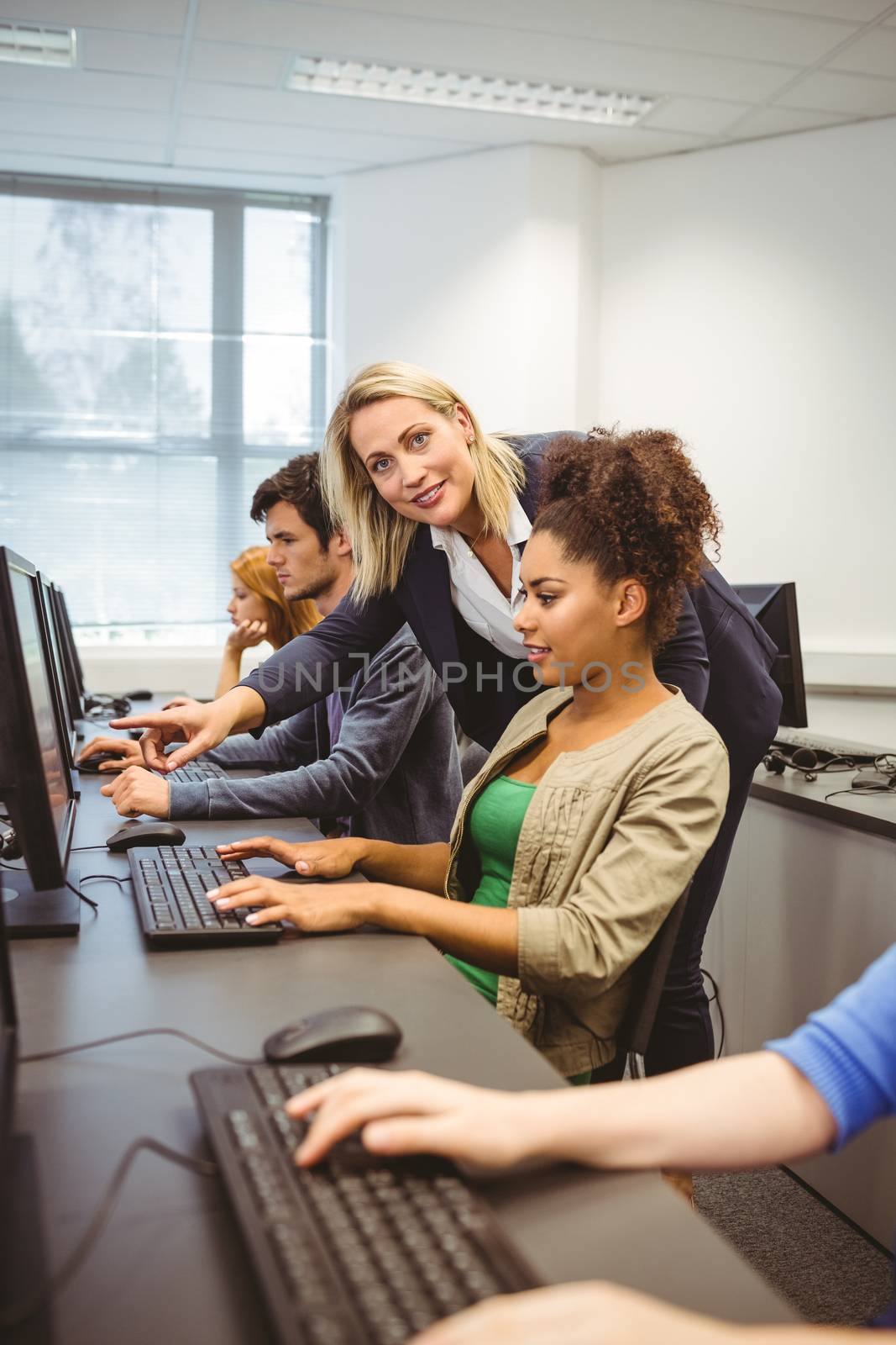 Happy computer teacher smiling at camera during her class by Wavebreakmedia