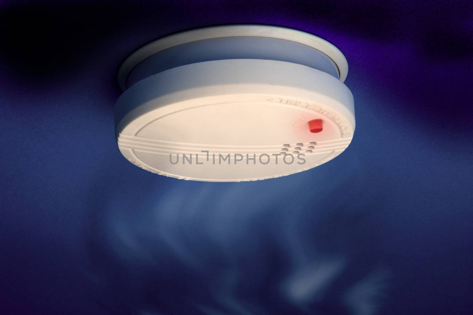 smoke detector with smoke and red light on the dark blue background