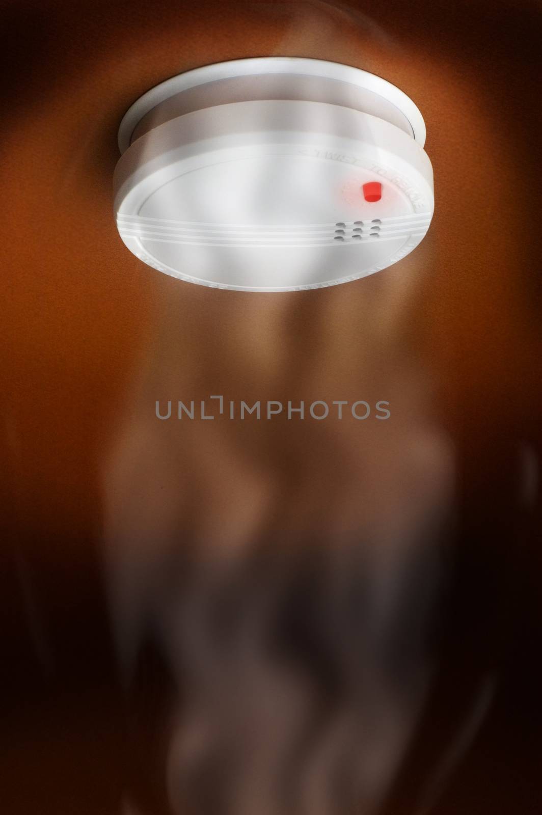 smoke detector with smoke and turned on the red light on a dark brown background