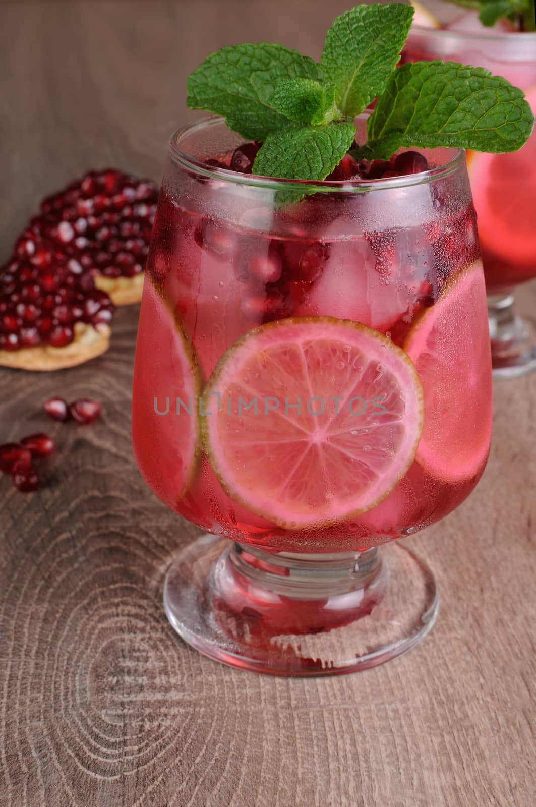 Pomegranate cocktail with slices of lime, mint and ice