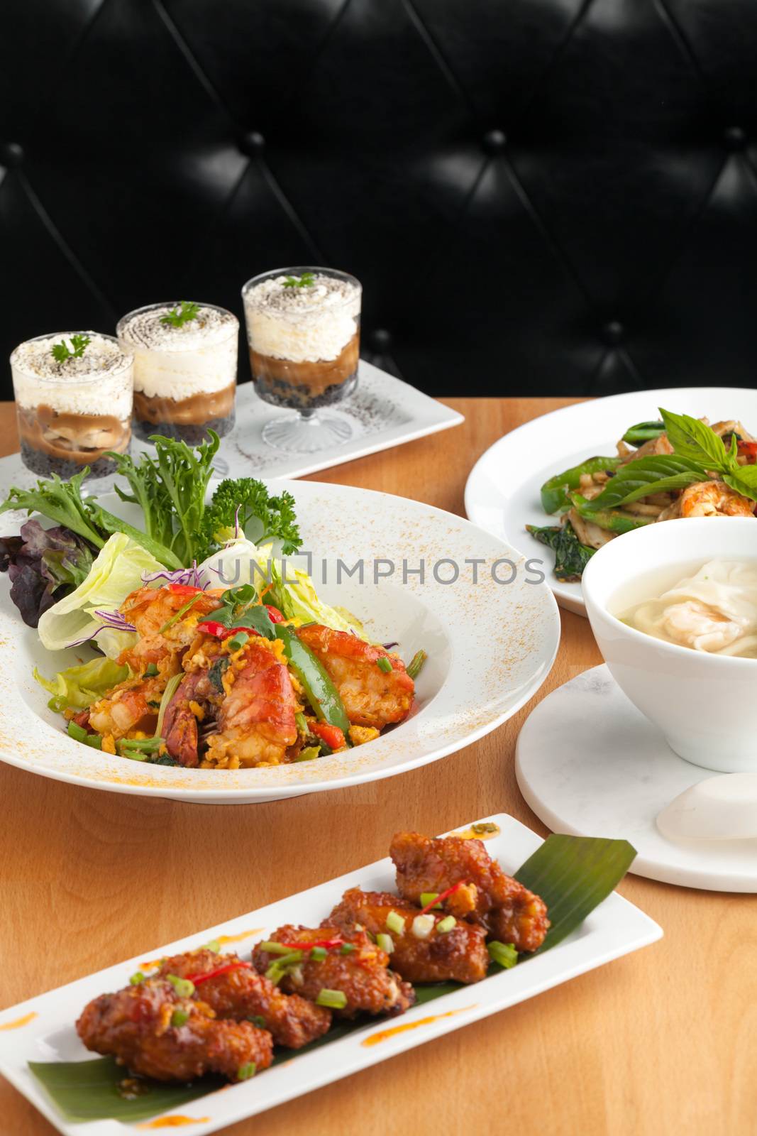 Varieties of Thai foods and appetizers covering a table. Shallow depth of field.