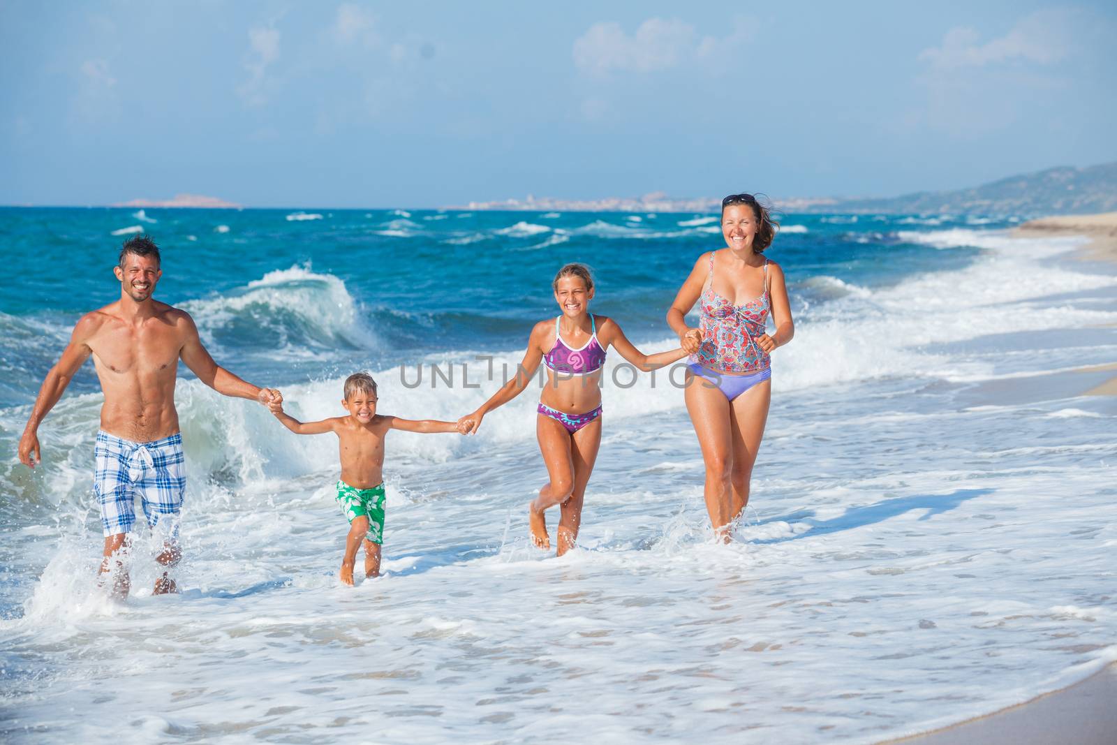 Happy family running on the sea with wave