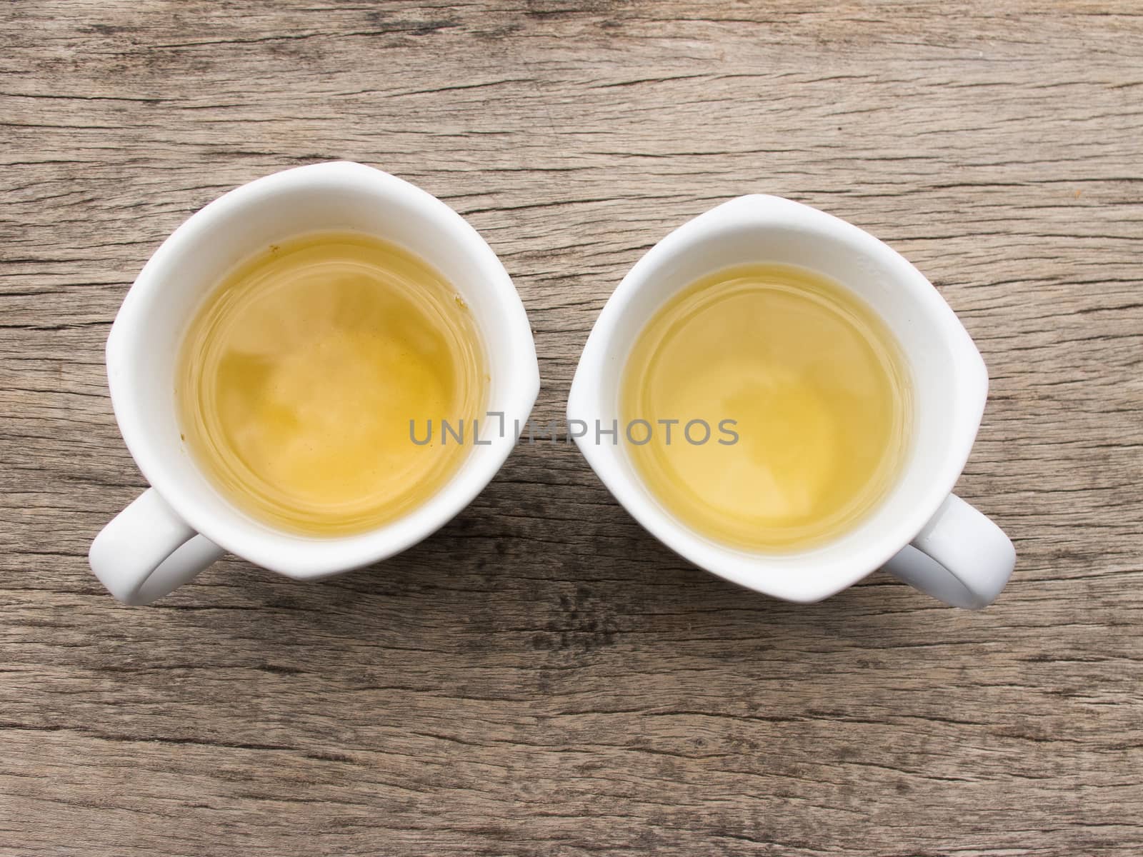 Two white teacup with tea on wood