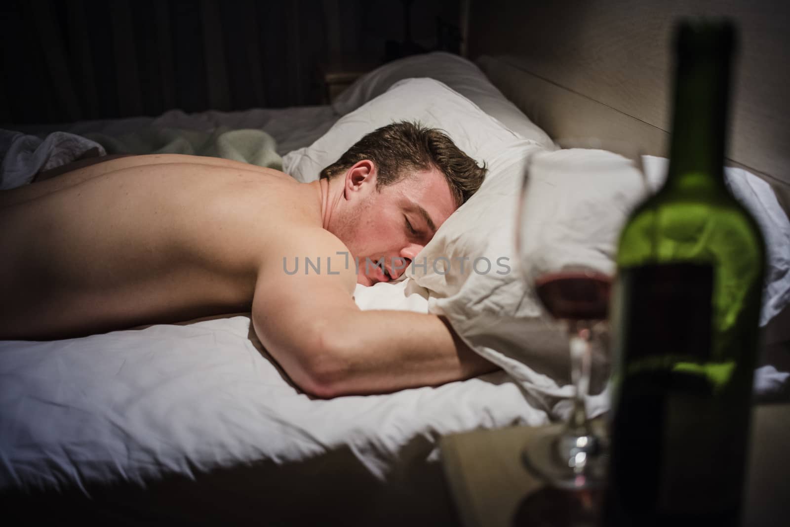 Hangover Man in a Bed at Night with a Wine Bottle