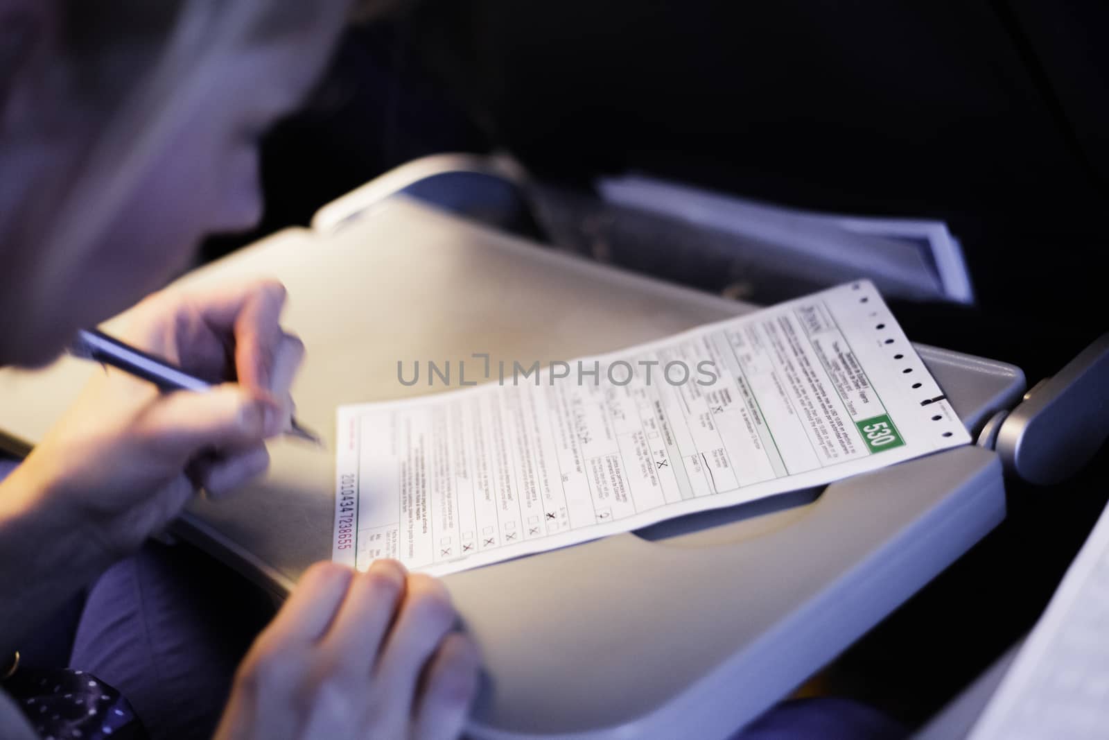 Woman Filling Document in the Airplane - blur motion of hand and personal informations erased.