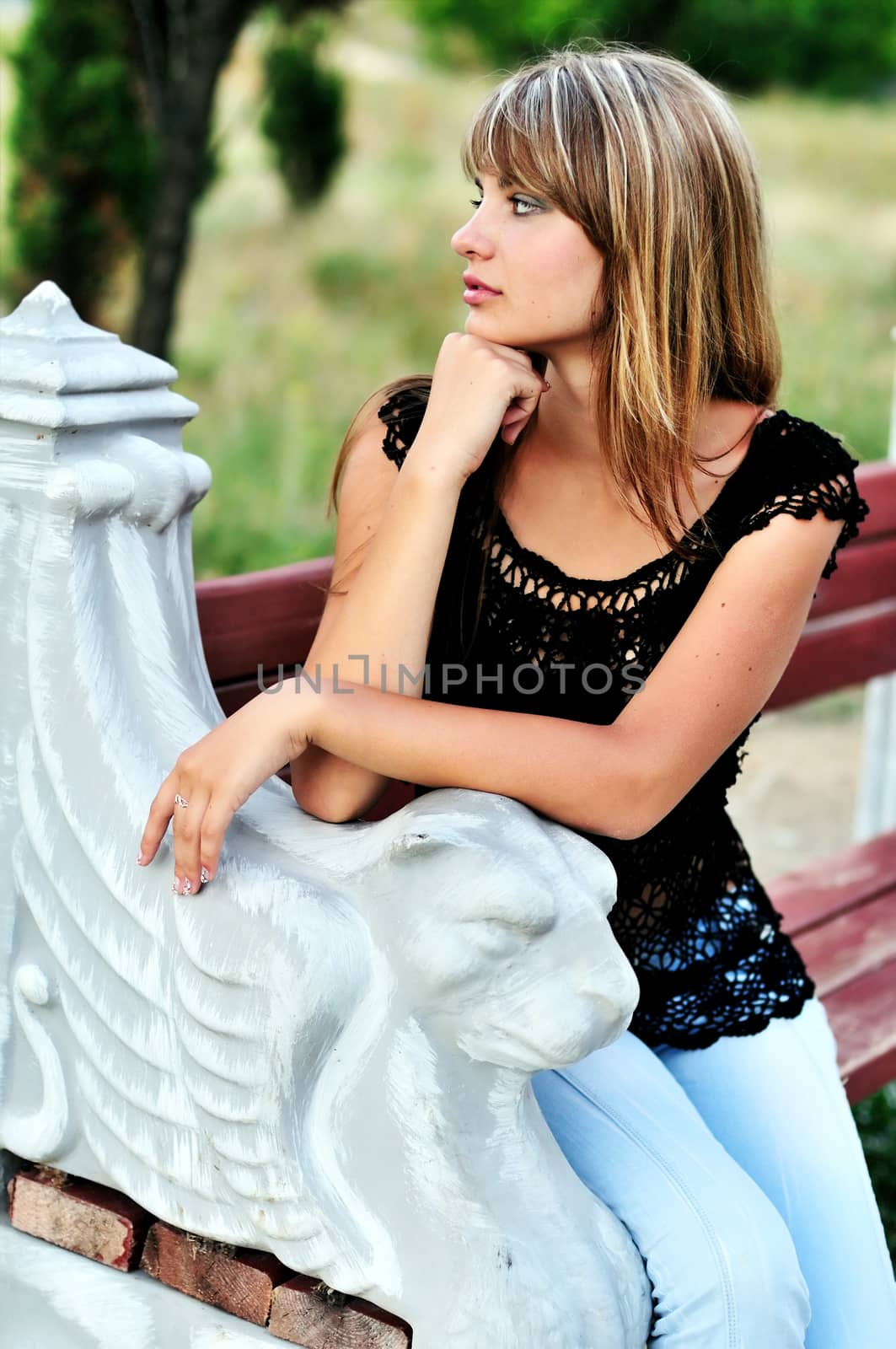 Beautiful tanned girl sitting on the bench 
