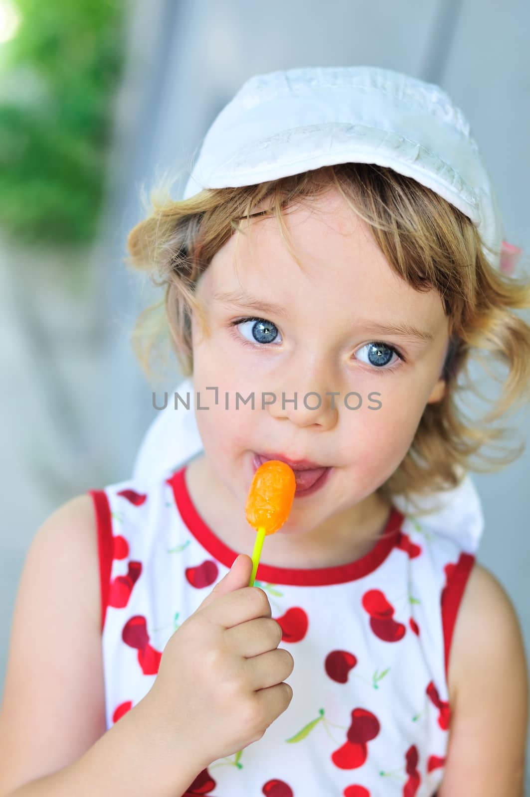 portrait of sweet girl with orange lollipop 