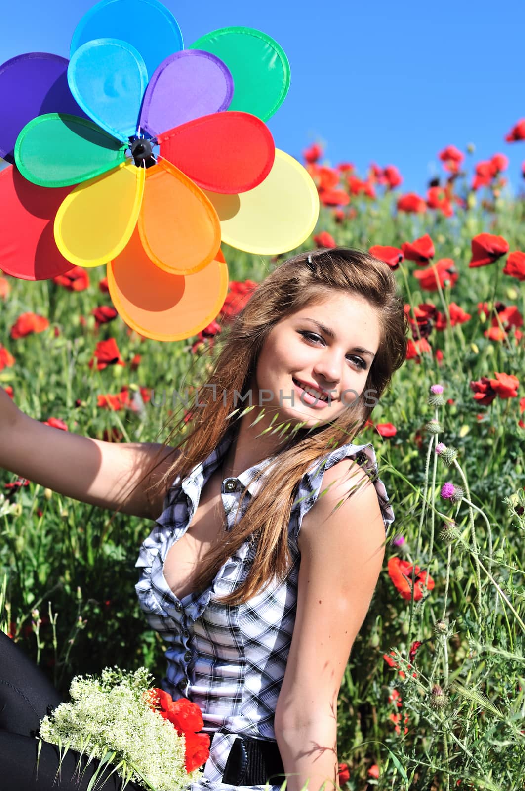 happy teen girl having fun with windmill on the poppy field 