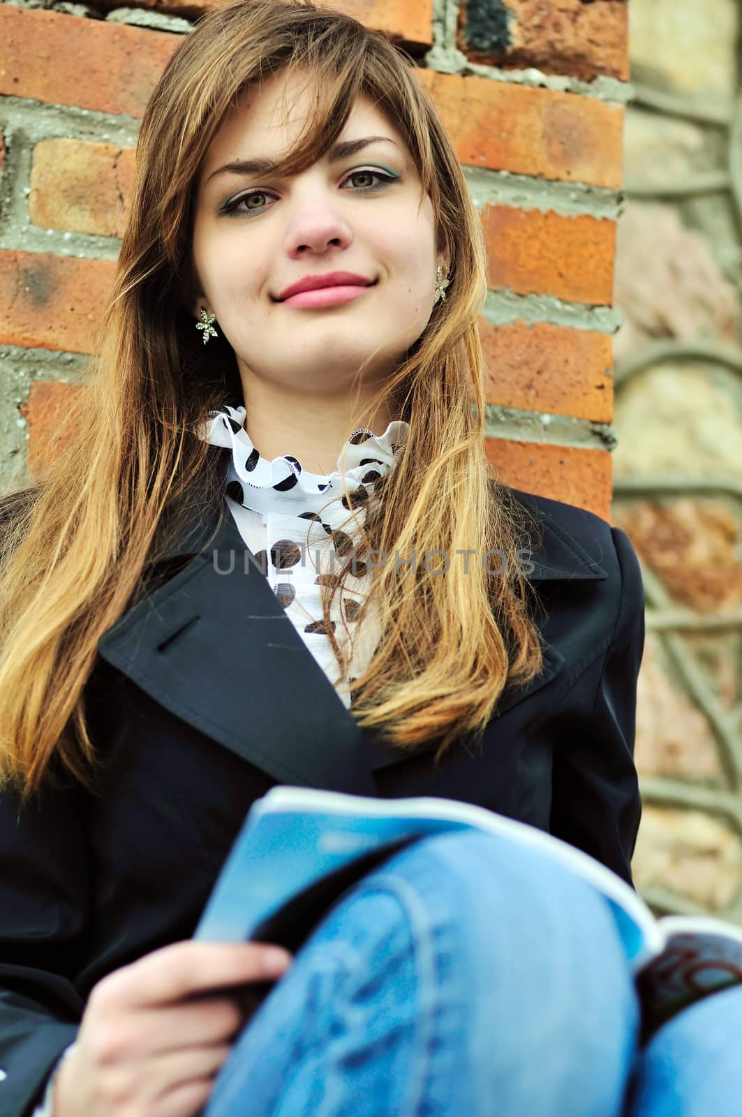 teen student girl reading near the brick wall 