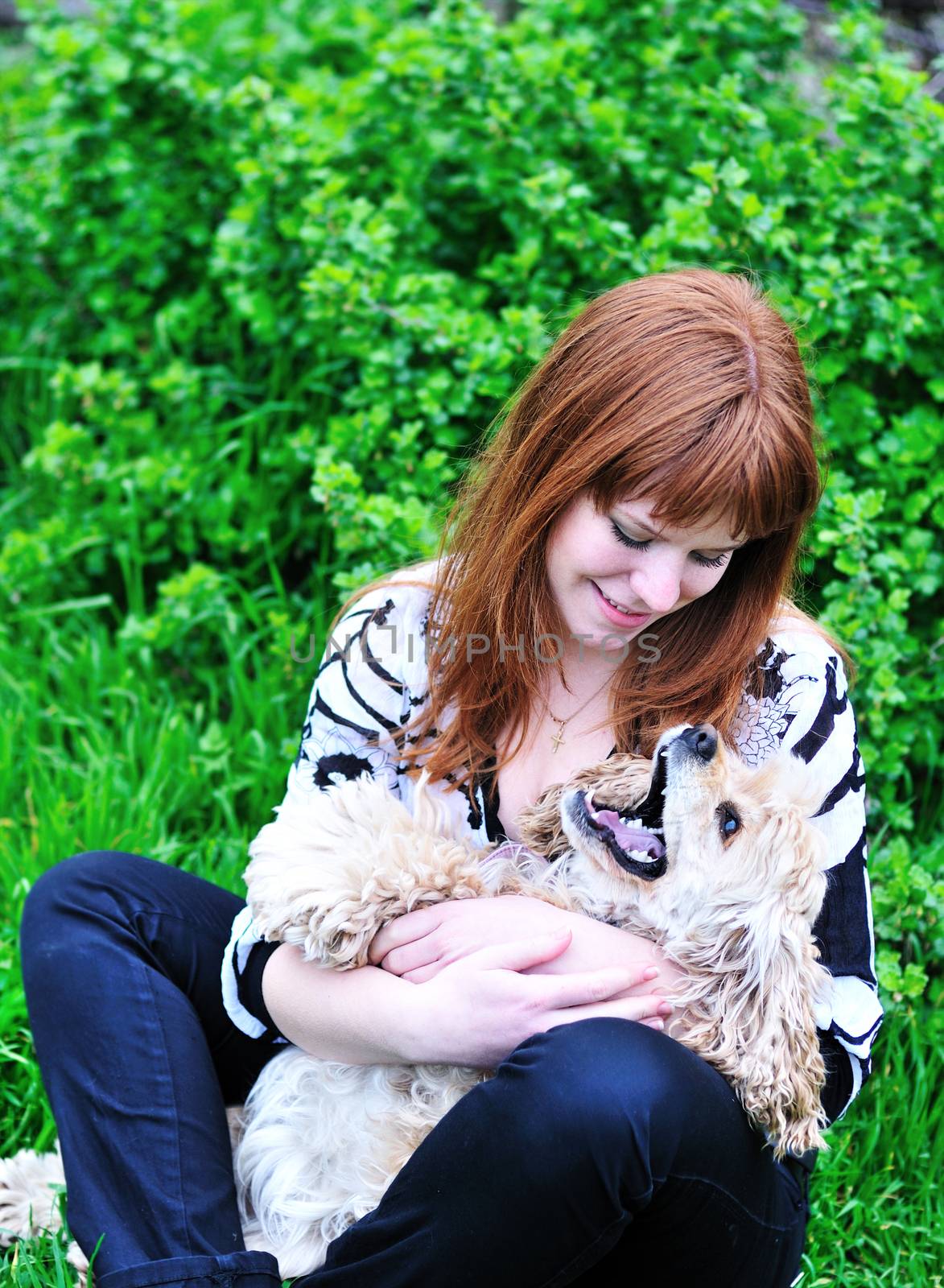 redheaded pretty girl playing with her dog on the meadow 