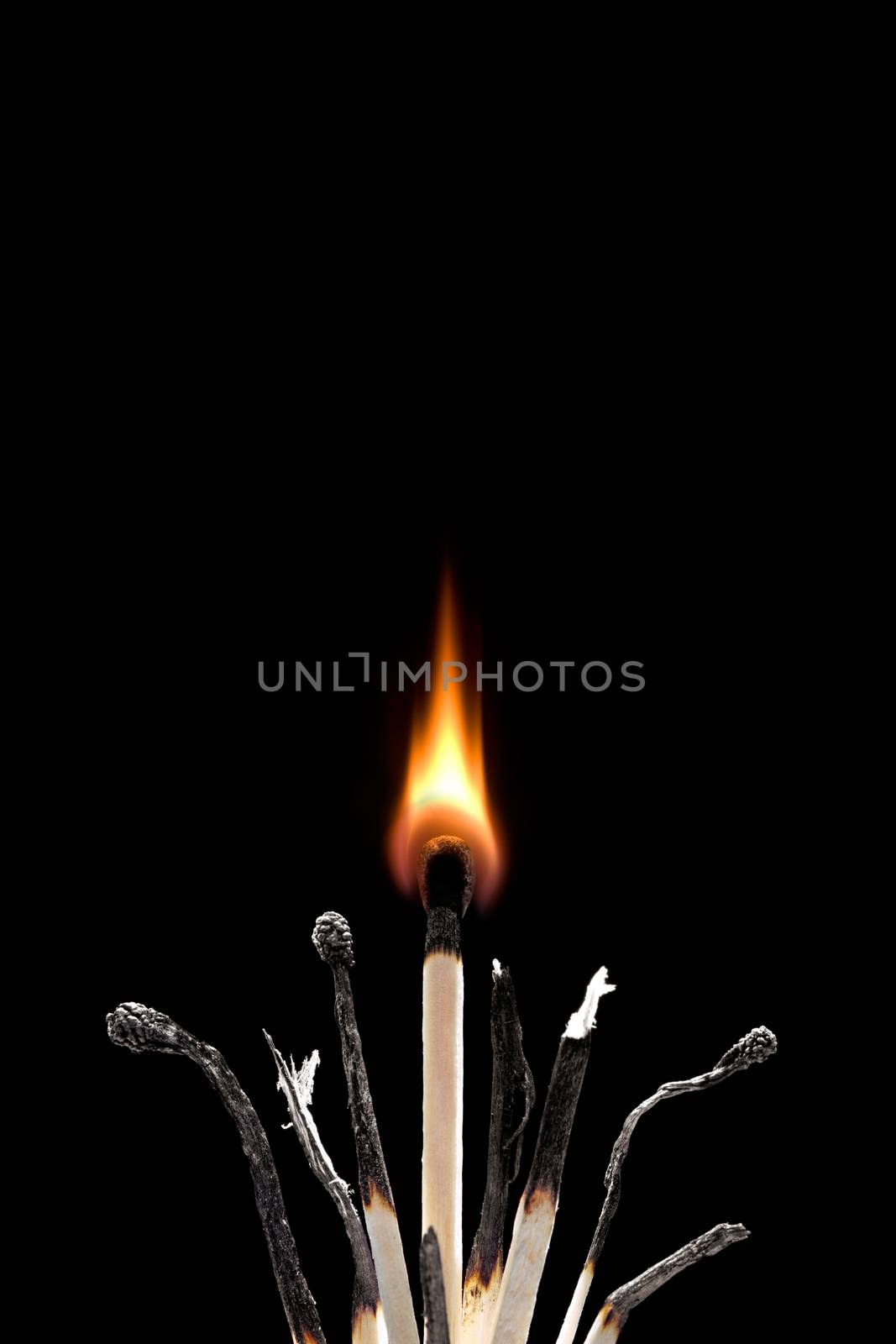 The spoiled matches on a black background. One match burns.