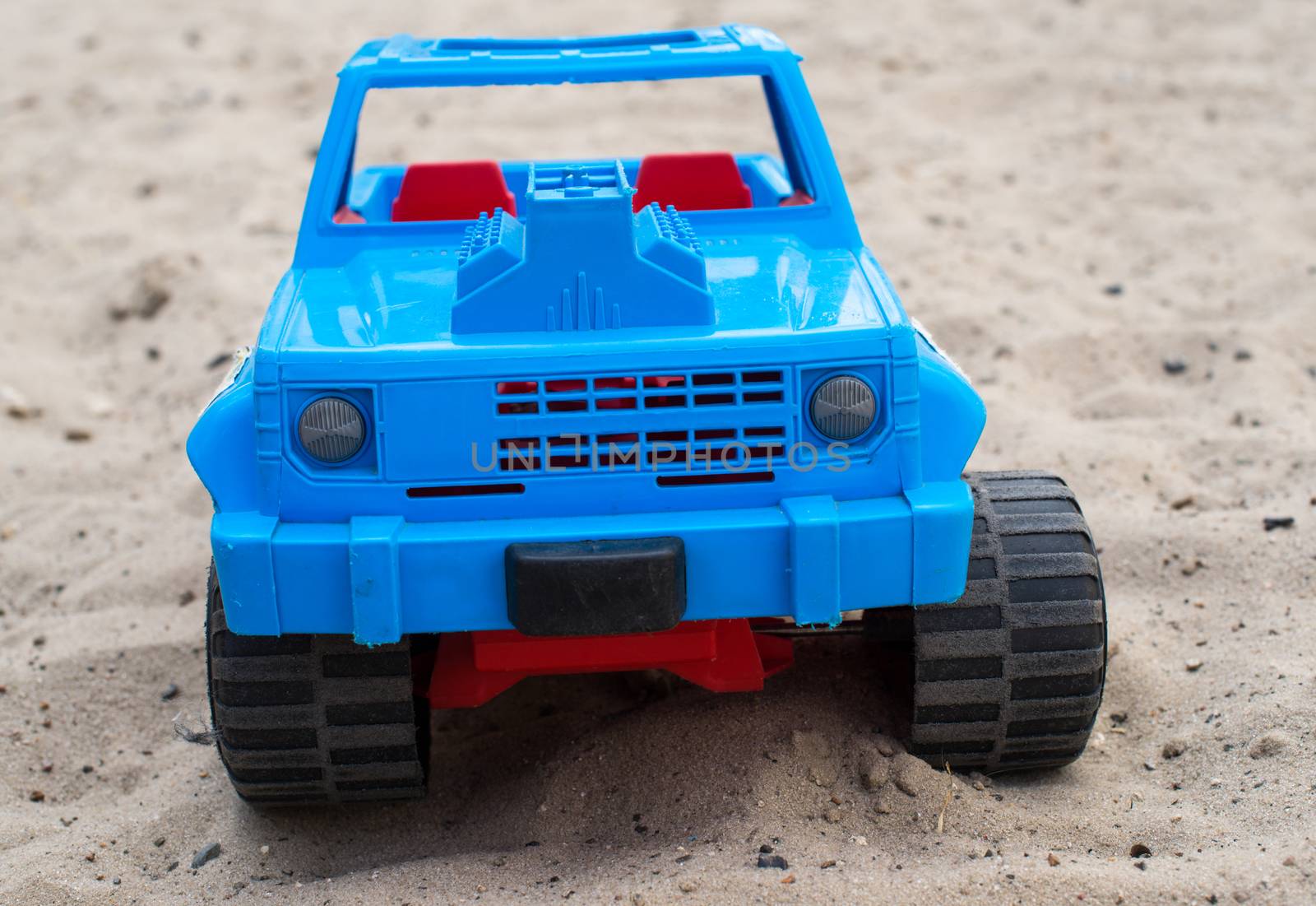 Blue toy car on the sand. Close up.