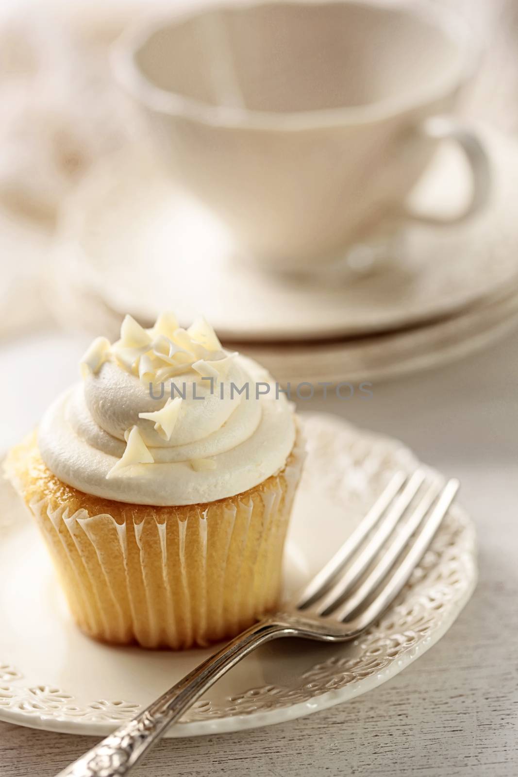 Closeup of vanilla cupcake with tea cup by Sandralise