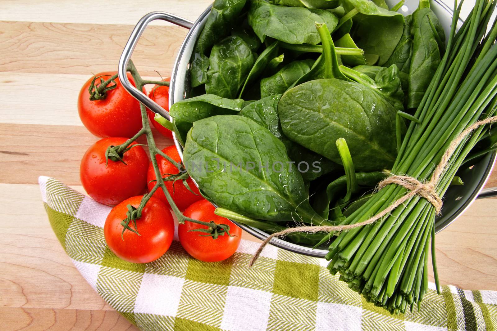 Fresh spinach leaves with tomatoes and strainer by Sandralise