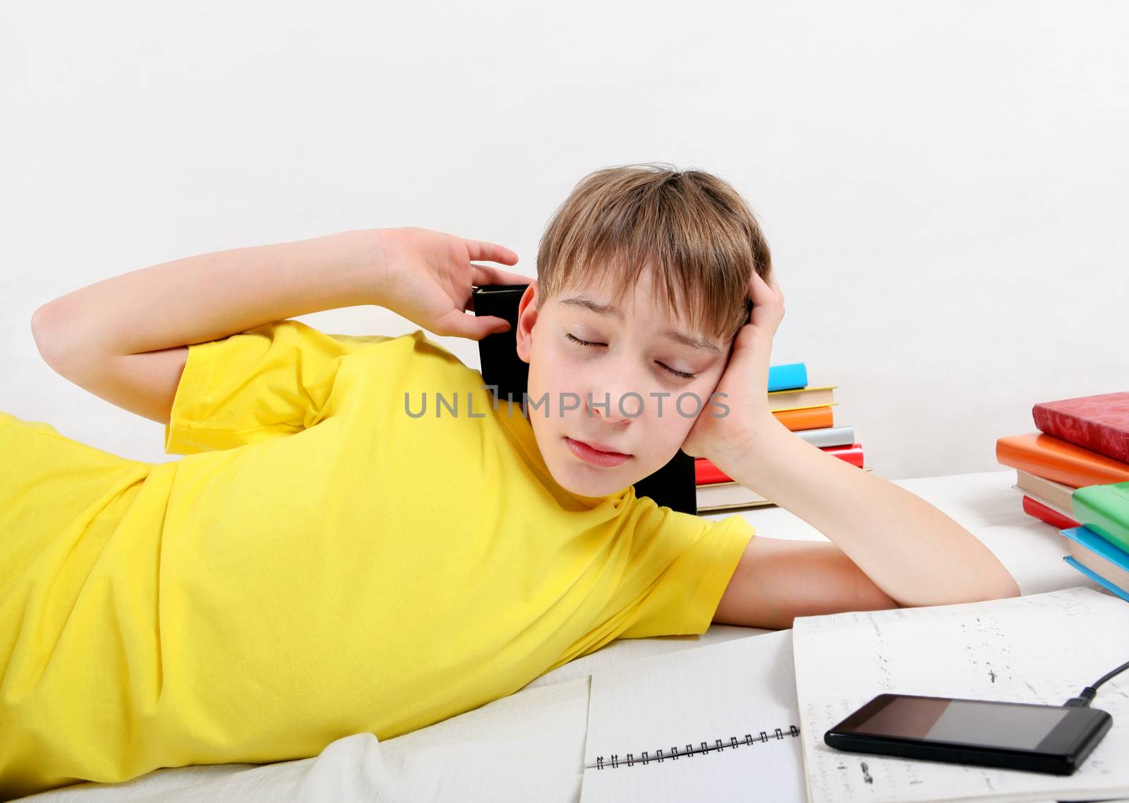 Tired Teenager doing Homework on the Sofa at the Home