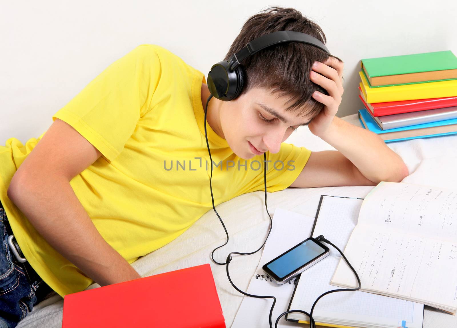 Cheerful Student listen the Music with the Books on the Bed