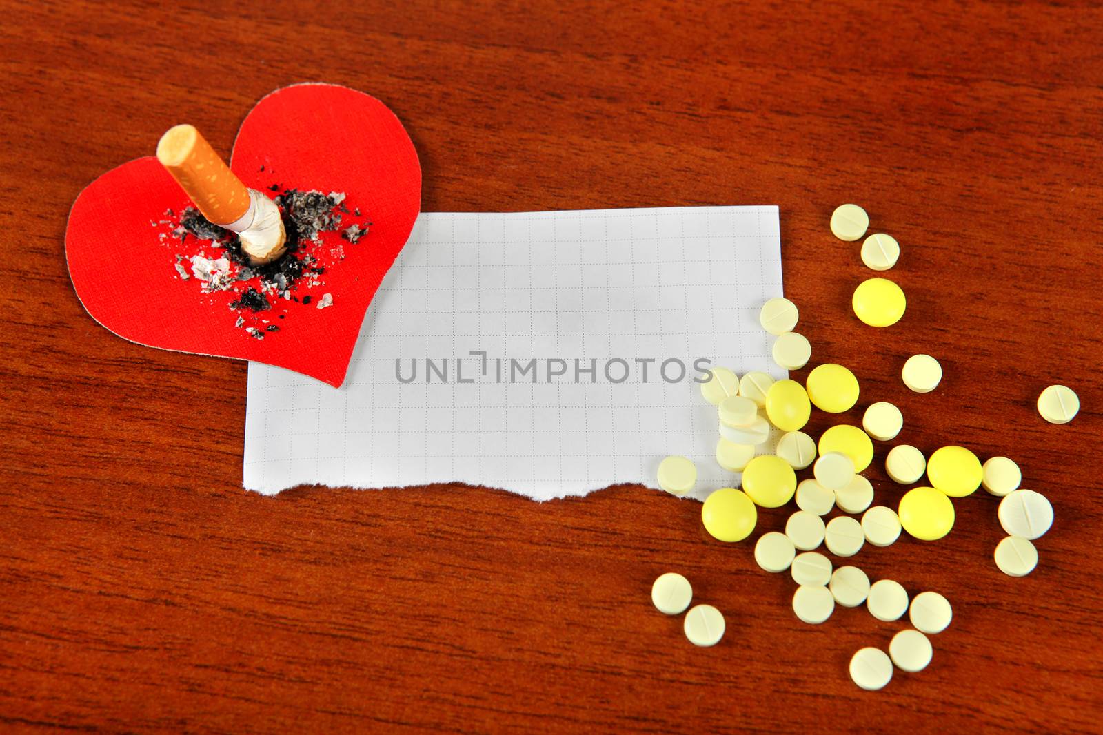 Cigarette in Heart Shape and Empty Paper with a Pills on the Table