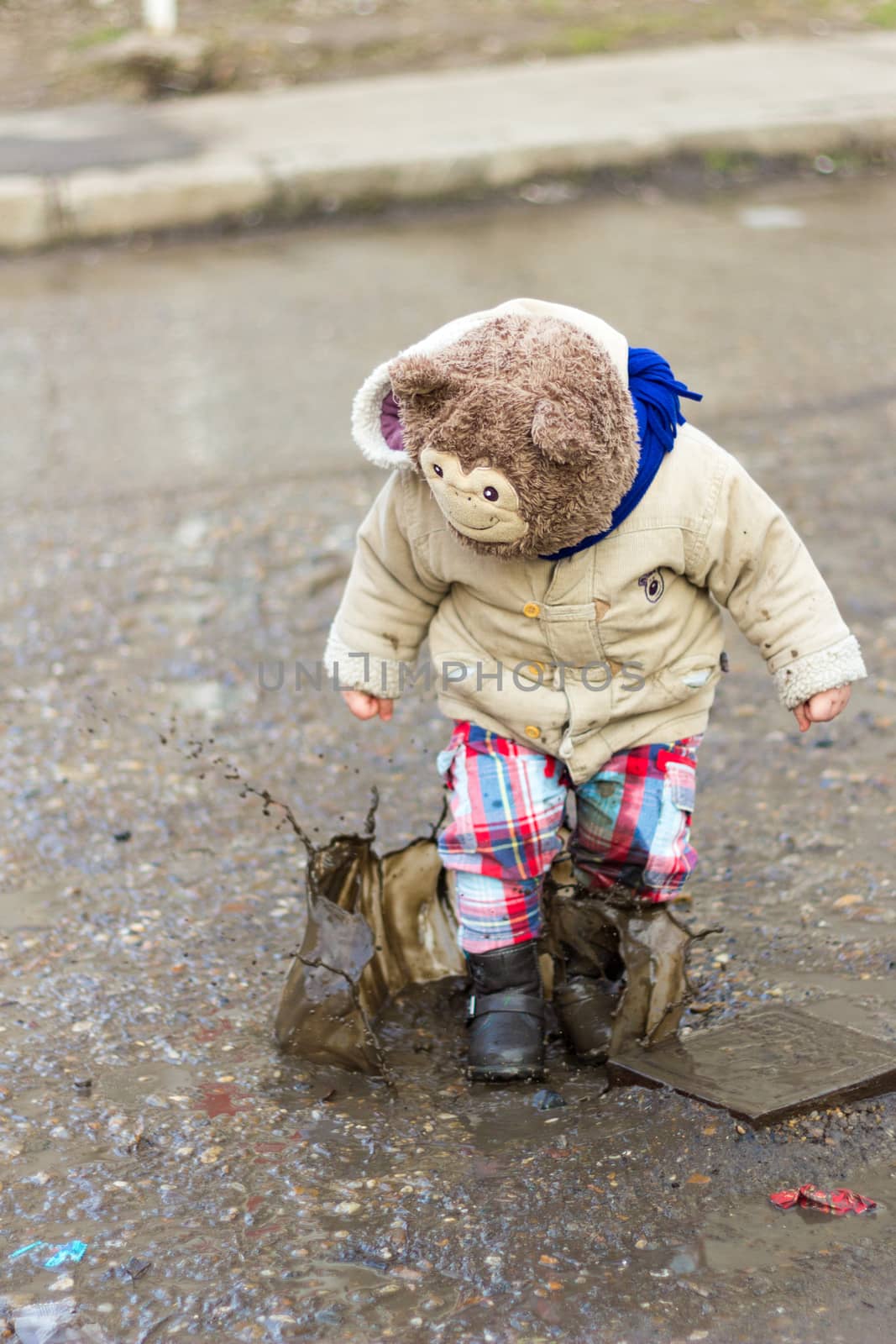 Kid playing in puddle on city street