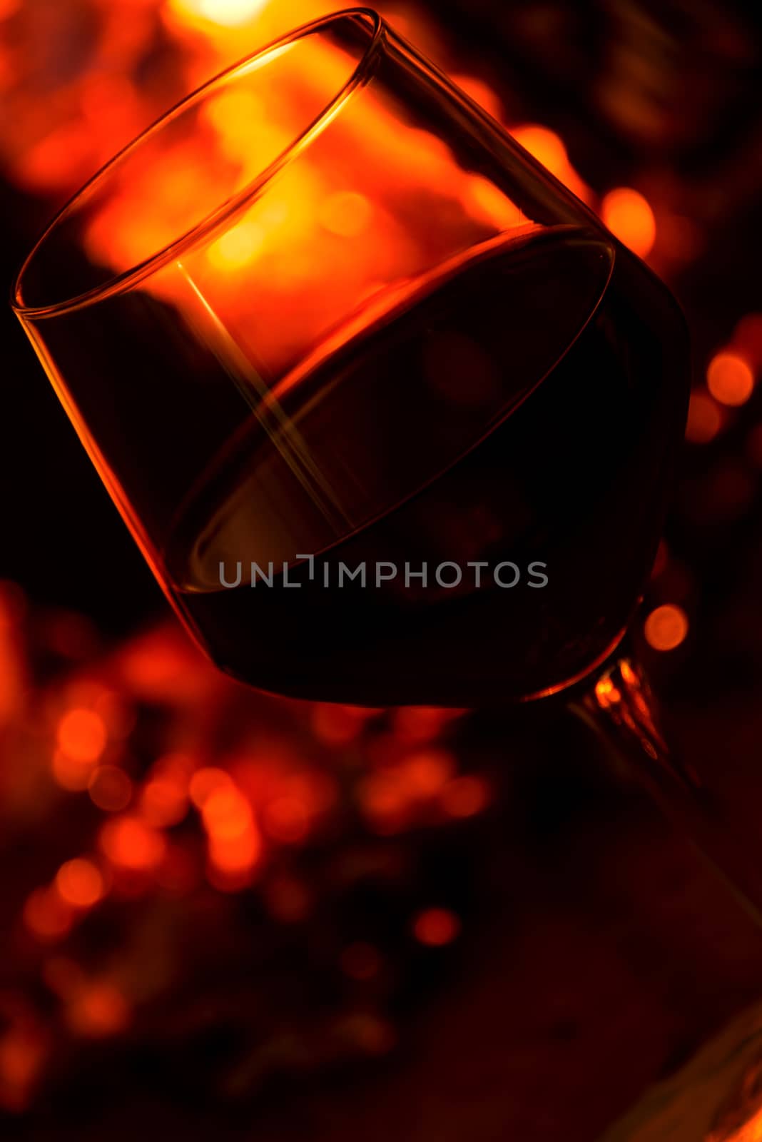 Glass of red vine near burning fireplace