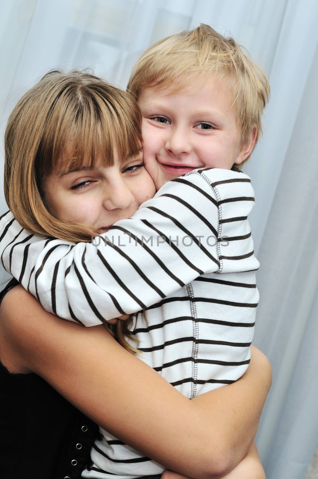 Brother and sister at home smiling and embracing 