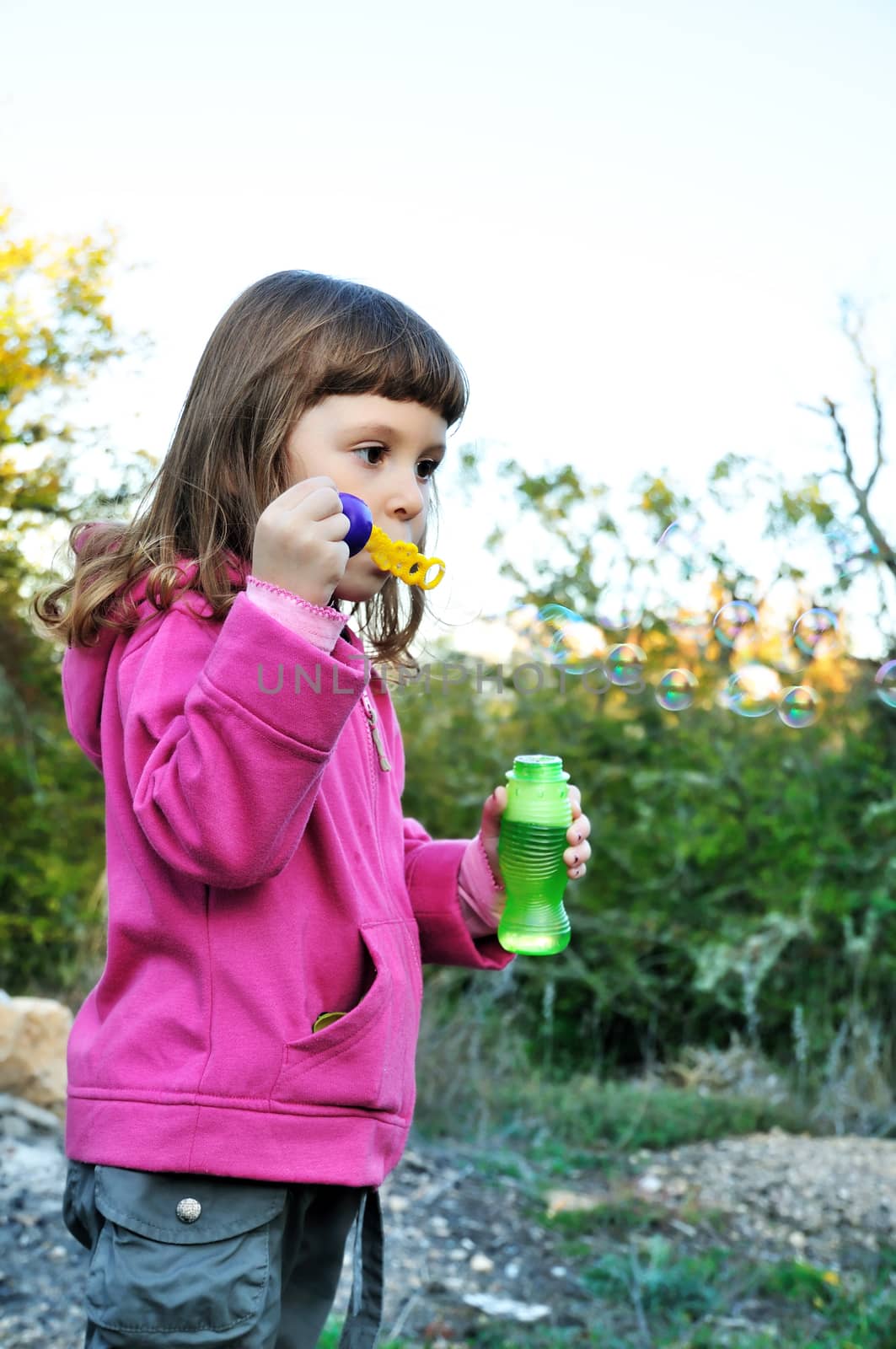 little girl blowing soap bubbles in autumn forest 