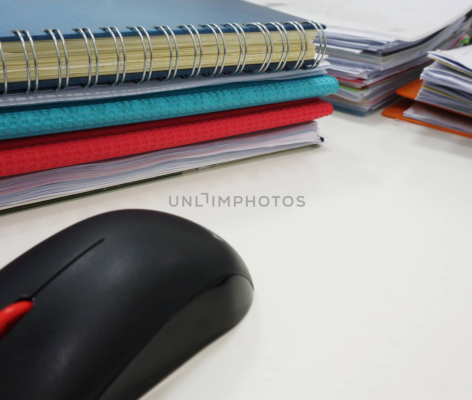 Set of documents on the desk and black computer mouse placed on the side.                               