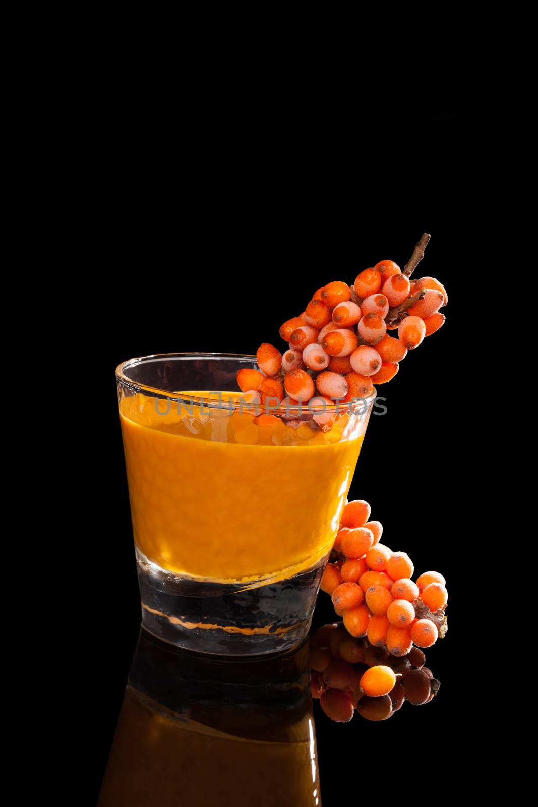 Sea buckthorn and sea buckthorn juice in glass isolated on black background. Healthy living, immune system booth.