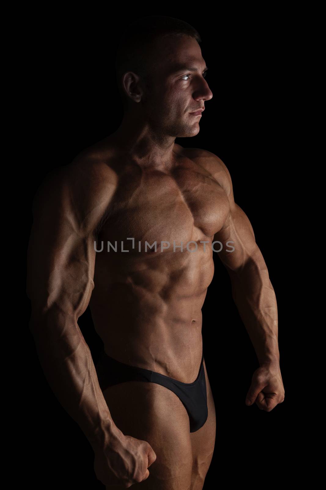 Sexy shirtless bodybuilder isolated on black background. Extreme strength, muscles and fitness.