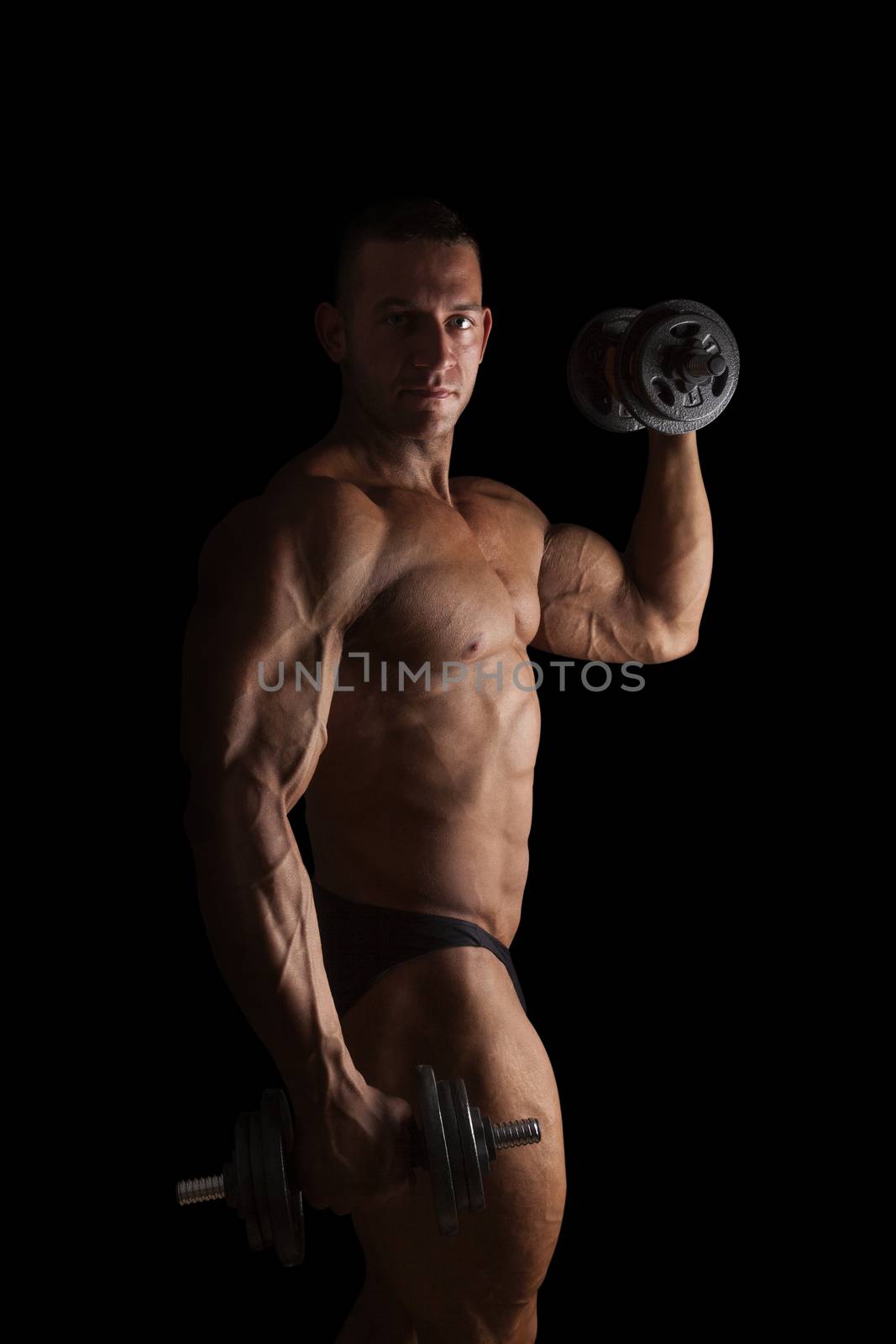 Sexy bodybuilder lifting weights and posing isolated on black background. Sport, weightlifting, bodybuilding and fitness. 