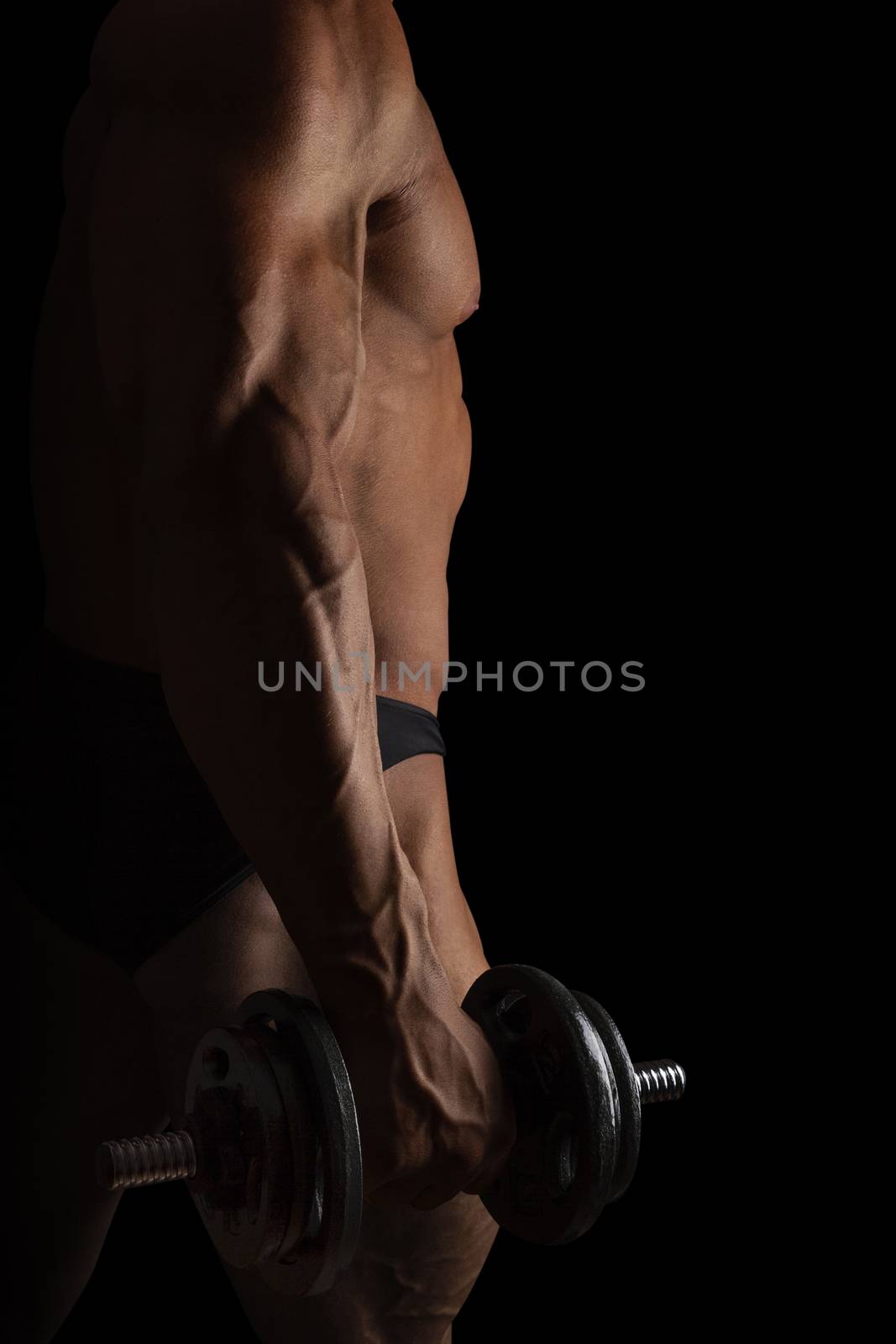 Sport and Fitness. Sexy bodybuilder holding dumbbell isolated on black background.