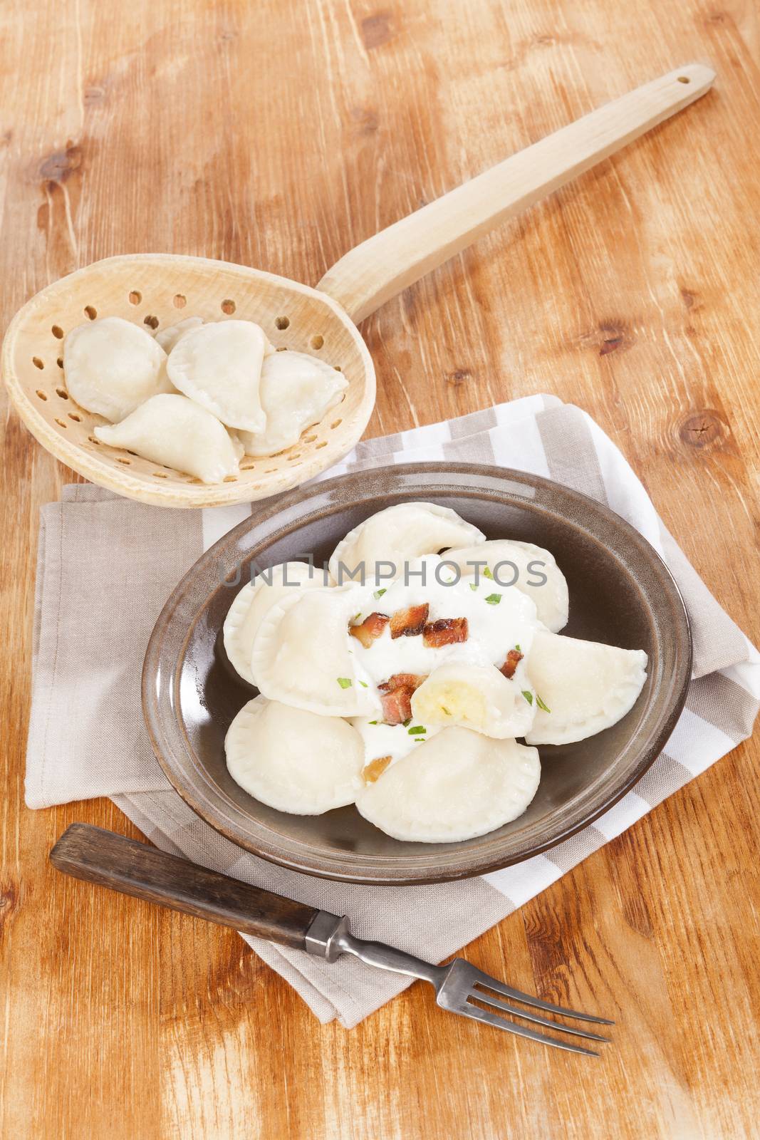 Bryndzove pirohy on wooden background with wooden scoop and fork. Vintage rustic style, traditional slovak eating. 