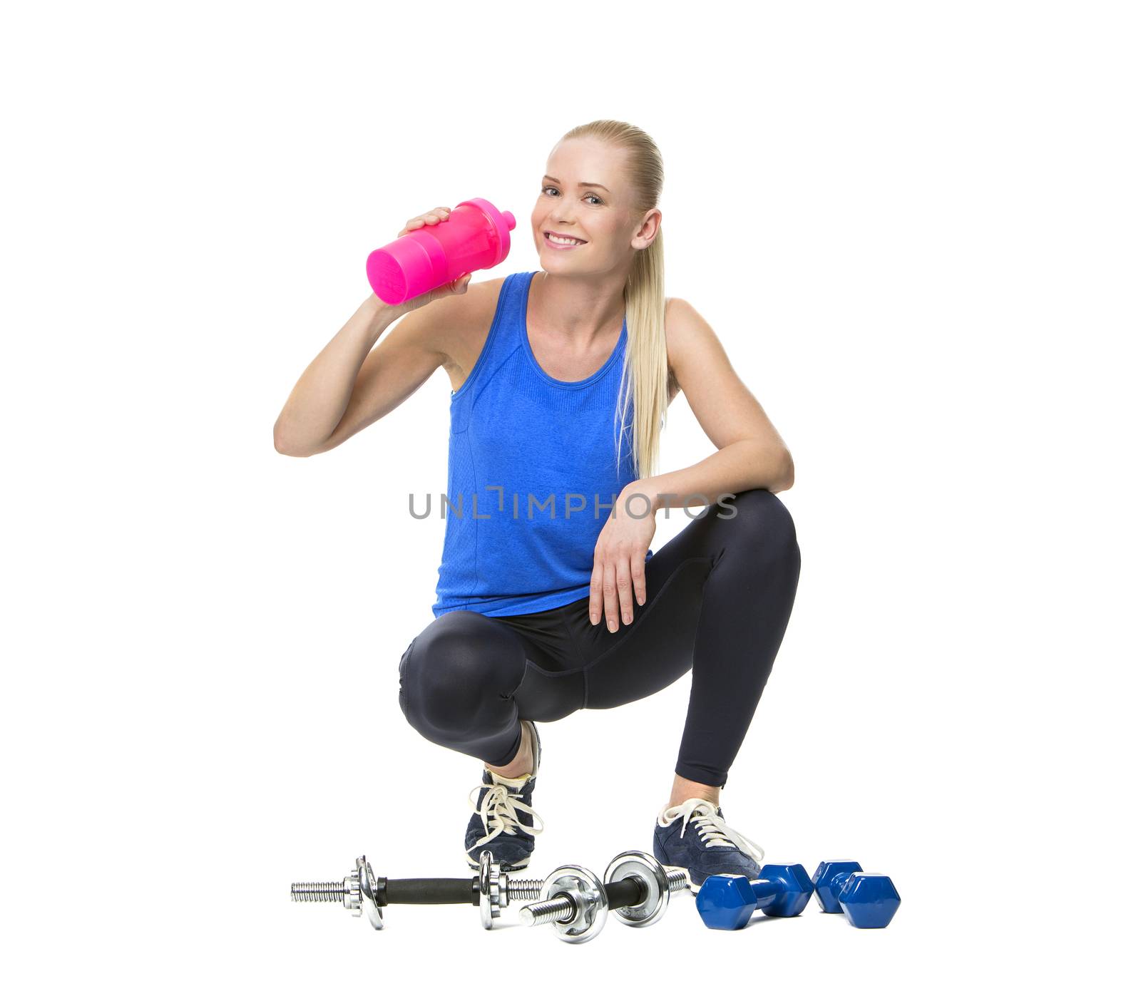 blonde woman wearing fitness clothing and drinking after exercising with weights