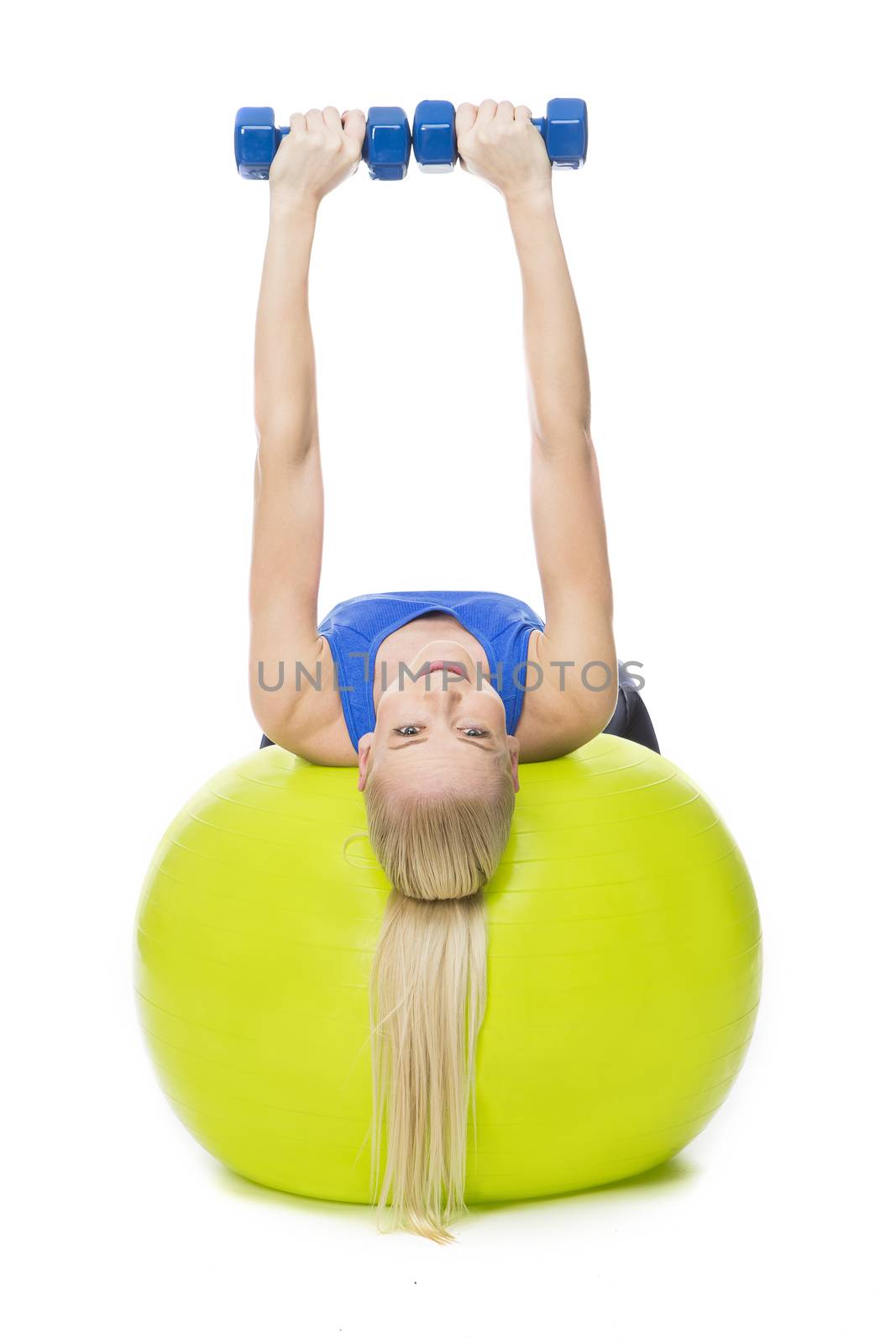 blonde woman wearing fitness clothing exercising with weights on a yellow ball